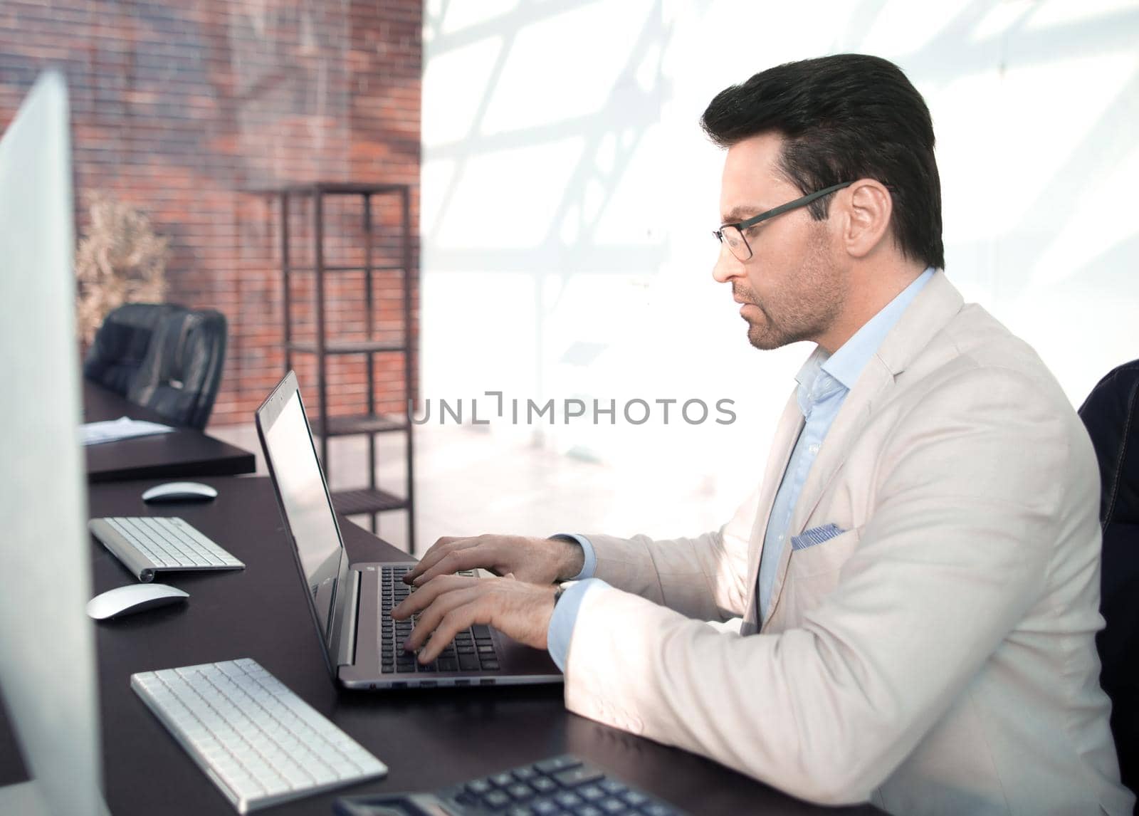 behind the glass.serious businessman typing on a laptop. business concept