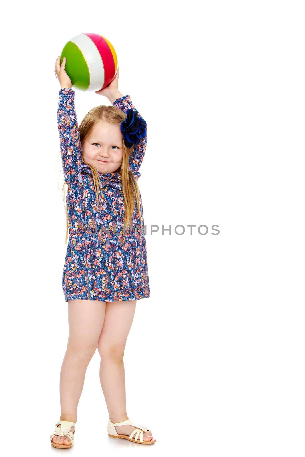 Funny little girl with long blond hair below the shoulders,which are attached to a large blue flower . In a short blue dress,holds ball over head - Isolated on white background