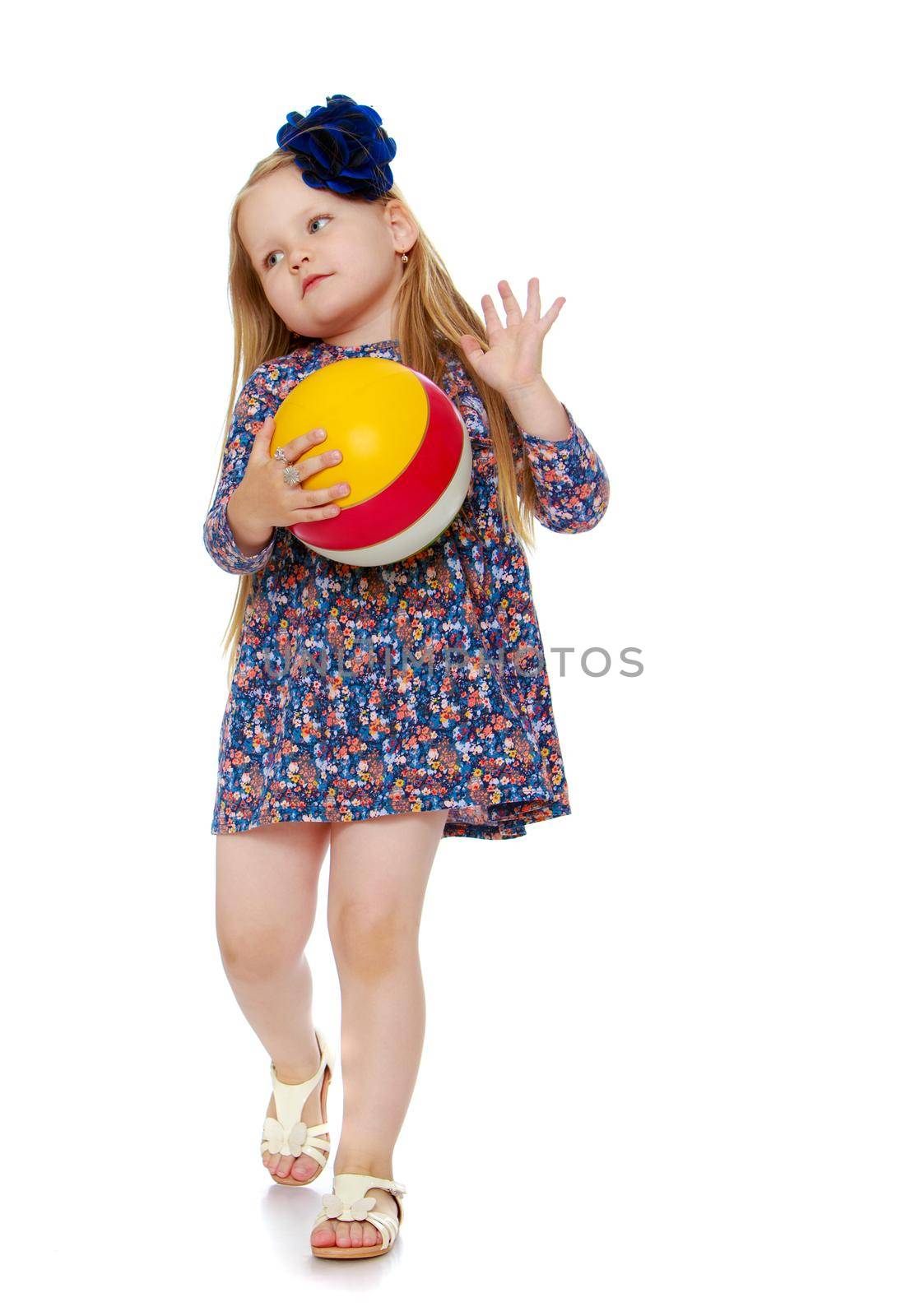 Shy little girl with long blond hair below the shoulders,which are attached to a large blue flower . In a short blue dress playing with a ball - Isolated on white background