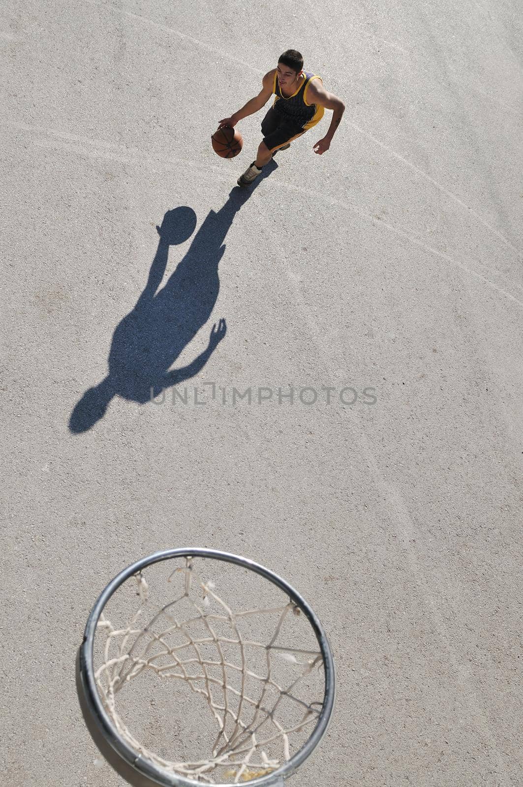 gorup of young boys who playing basketball outdoor on street with long shadows and bird view perspective