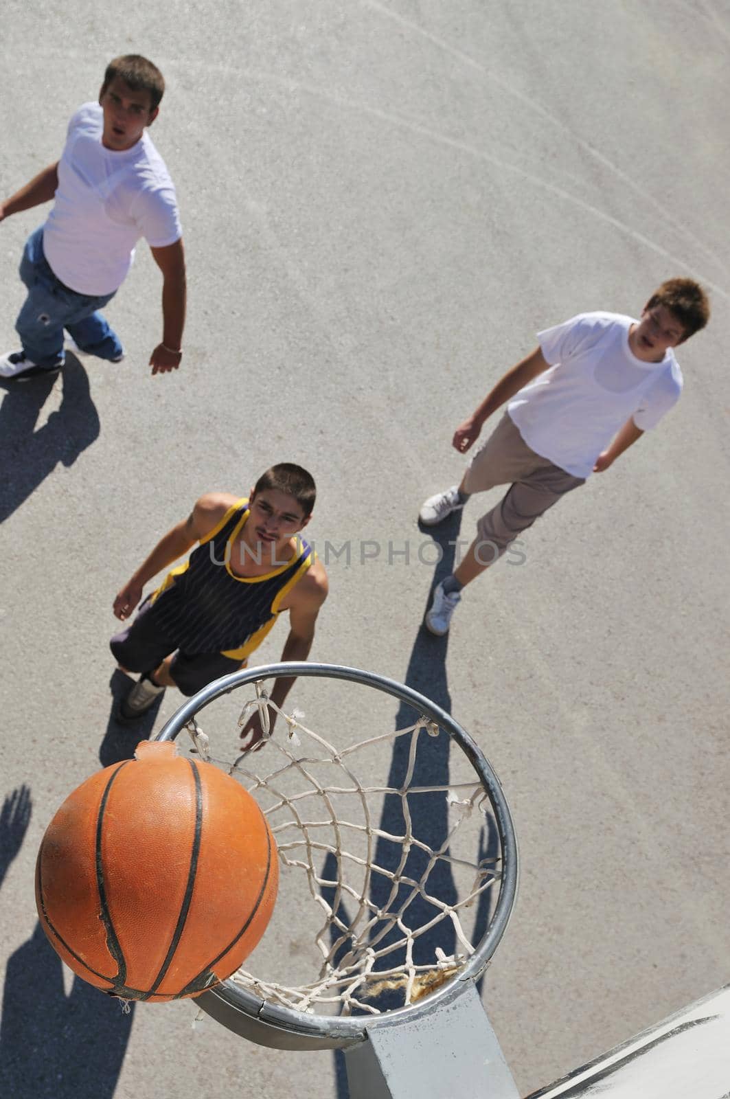 gorup of young boys who playing basketball outdoor on street with long shadows and bird view perspective