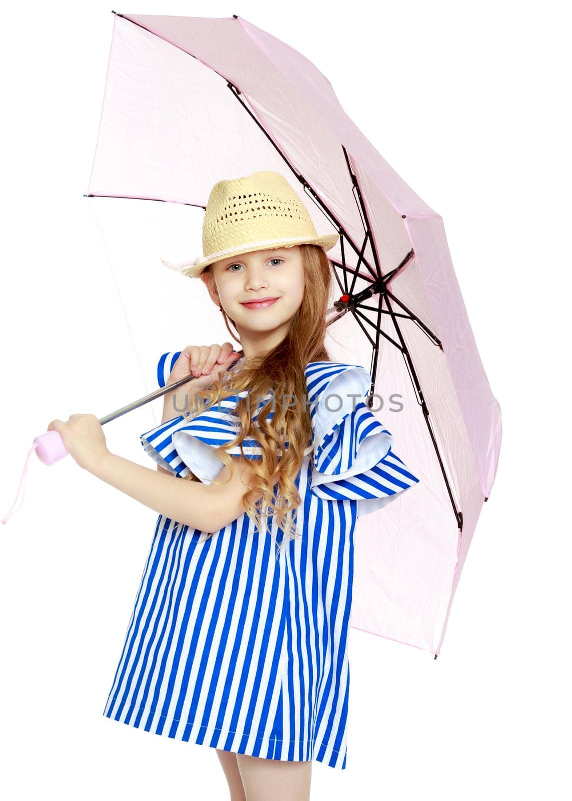 A stylish little girl with long blond hair in a very short, striped, summer blue dress and a straw hat.With a pink umbrella behind her shoulders.Isolated on white background.