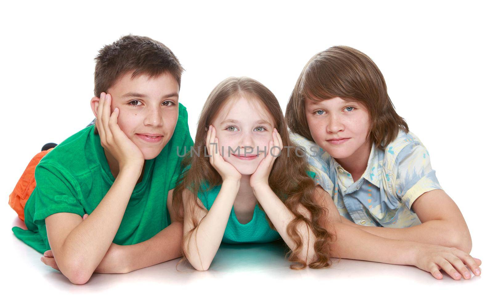 Three children lie on the floor and looking directly at the camera - Isolated on white background