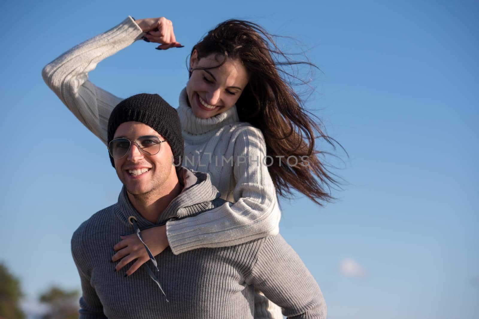 Men Giving Piggy Back Rides his girlfriend At Sunset By The Sea, autumn time