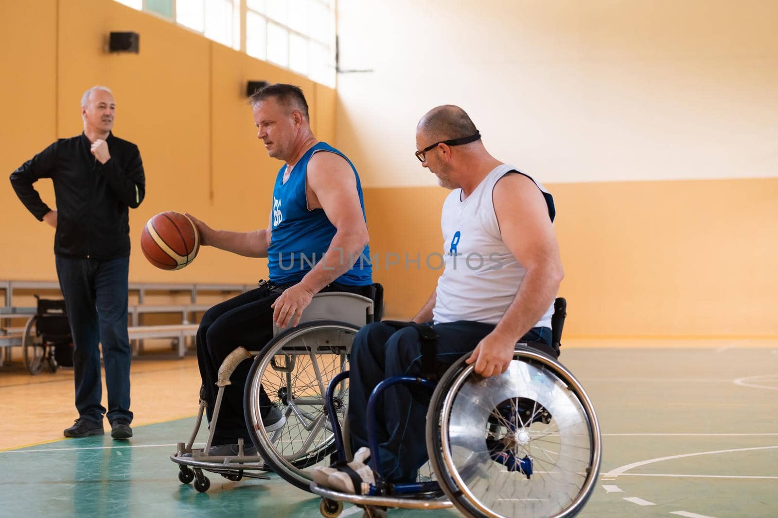 handicapped war veterans in wheelchairs with professional equipment play basketball match in the hall.the concept of sports with disabilities by dotshock