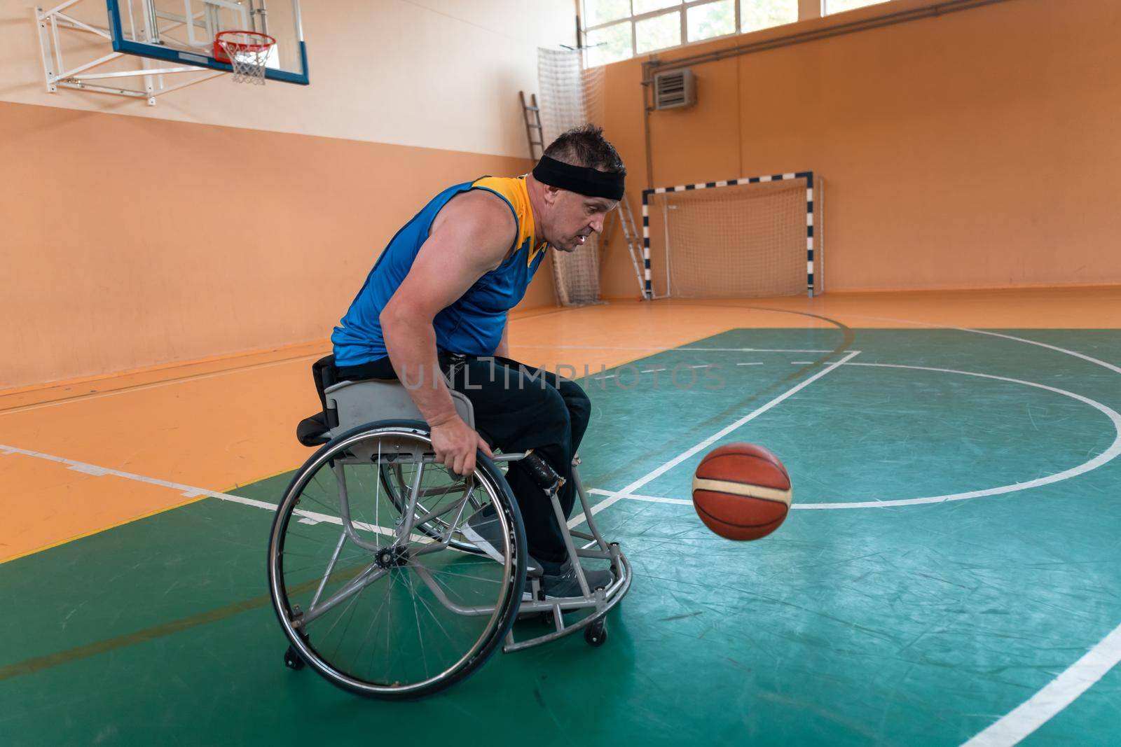 Disabled War veterans mixed race and age basketball teams in wheelchairs playing a training match in a sports gym hall. Handicapped people rehabilitation and inclusion concept by dotshock