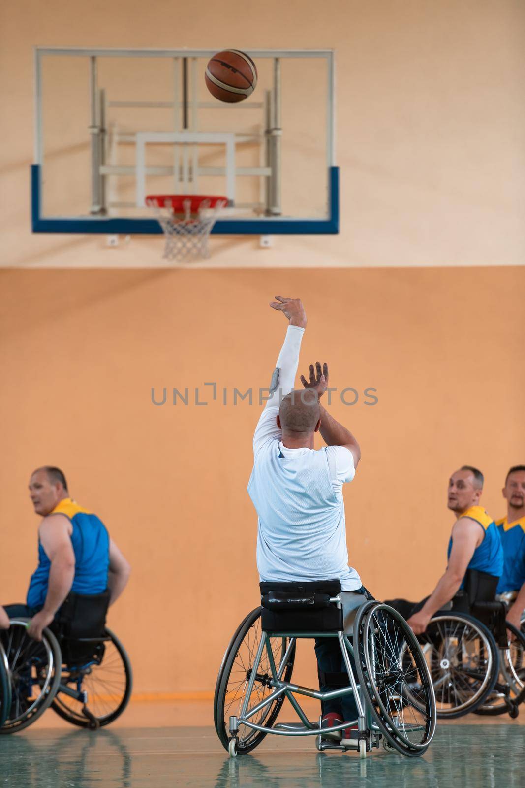 Disabled War or work veterans mixed race and age basketball teams in wheelchairs playing a training match in a sports gym hall. Handicapped people rehabilitation and inclusion concept.Hi quality photo