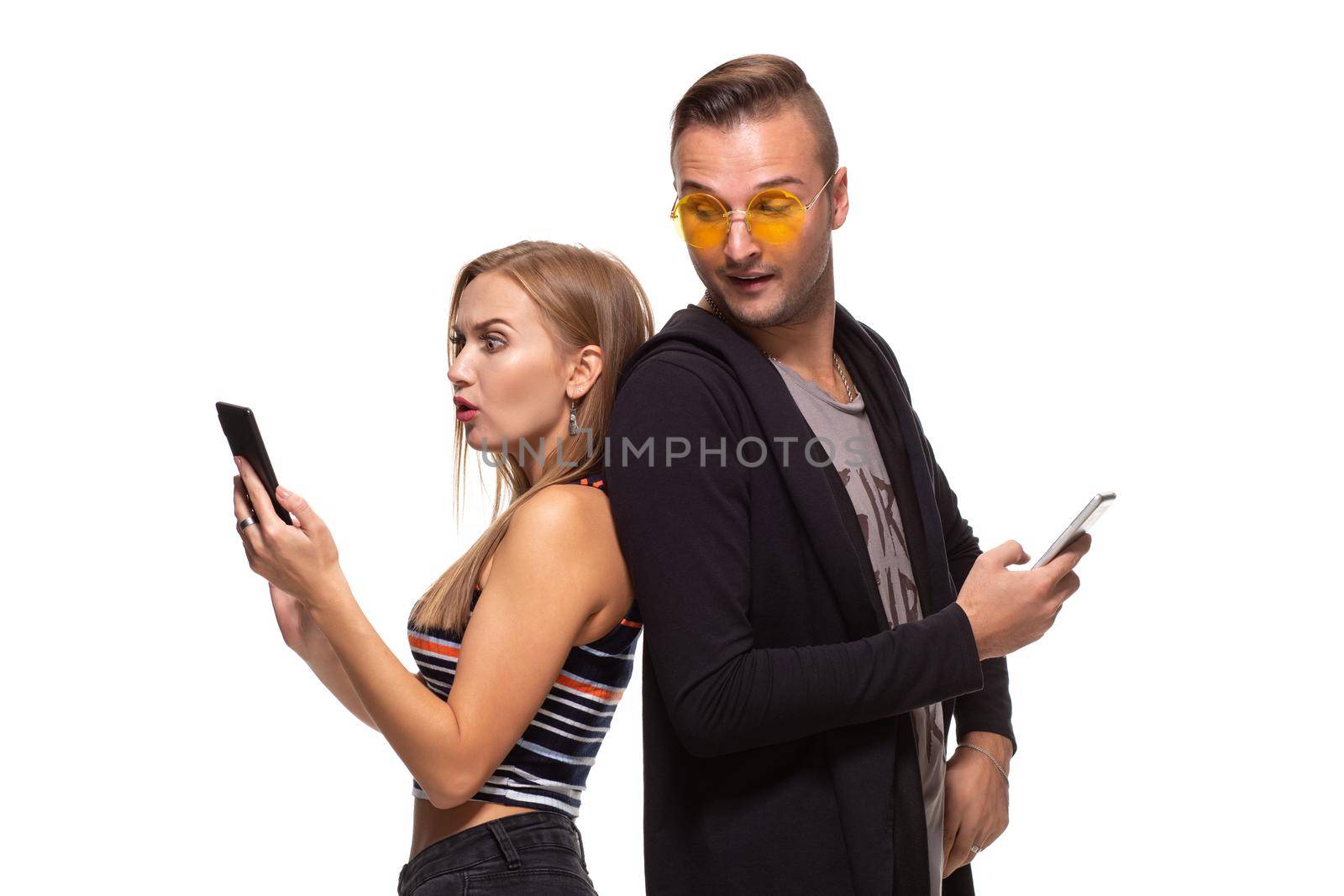 Man and woman stand with their backs to each other with telephones in their hands on white background. Studio shot