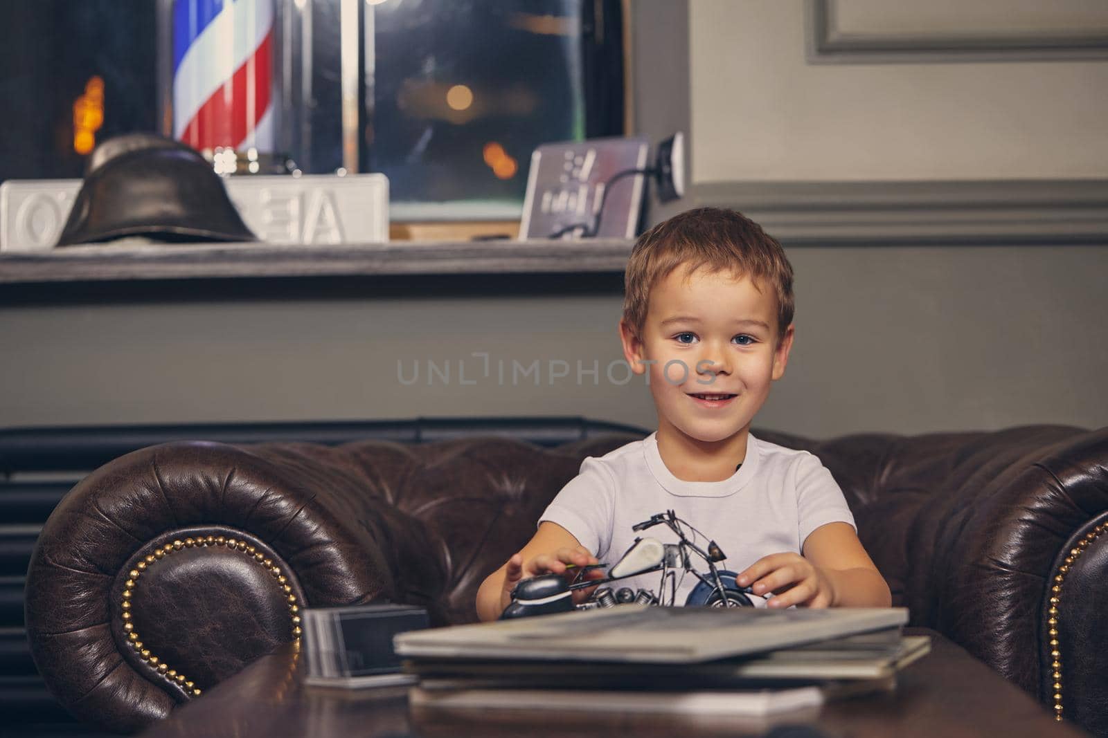 Little boy at the barbershop, in waiting room waiting for master. by nazarovsergey