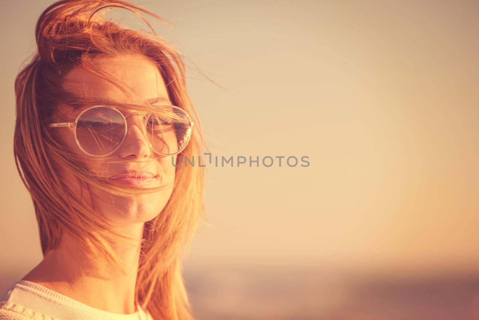 Young woman on the beach. The girl enjoying the warm autumn day. Portrait of beautiful girl near the water