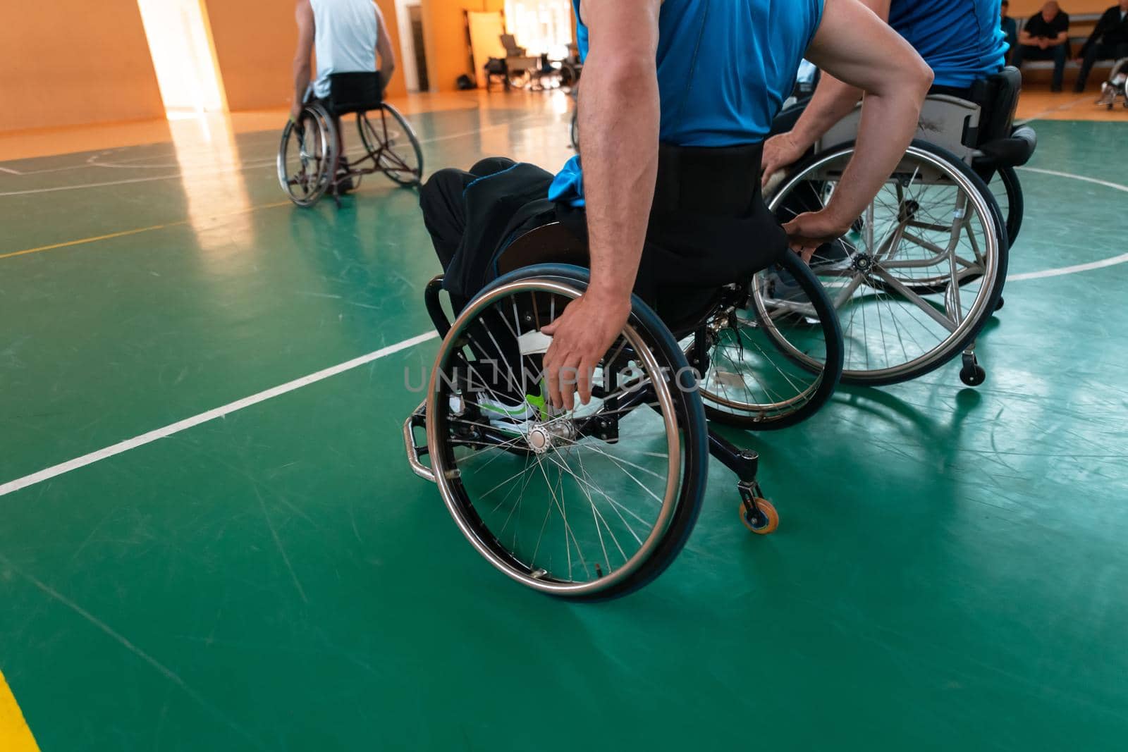 Close up photo of wheelchairs and handicapped war veterans playing basketball on the court by dotshock