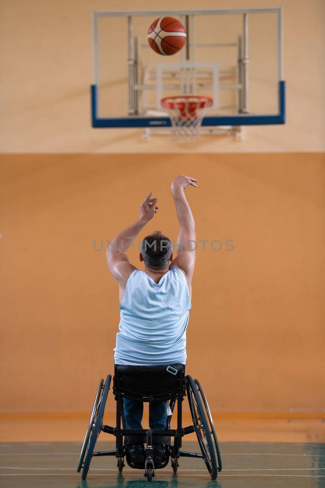 a war invalid in a wheelchair trains with a ball at a basketball club in training with professional sports equipment for the disabled. the concept of sport for people with disabilities by dotshock