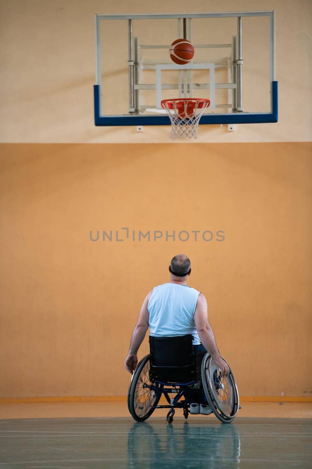 a war invalid in a wheelchair trains with a ball at a basketball club in training with professional sports equipment for the disabled. the concept of sport for people with disabilities by dotshock