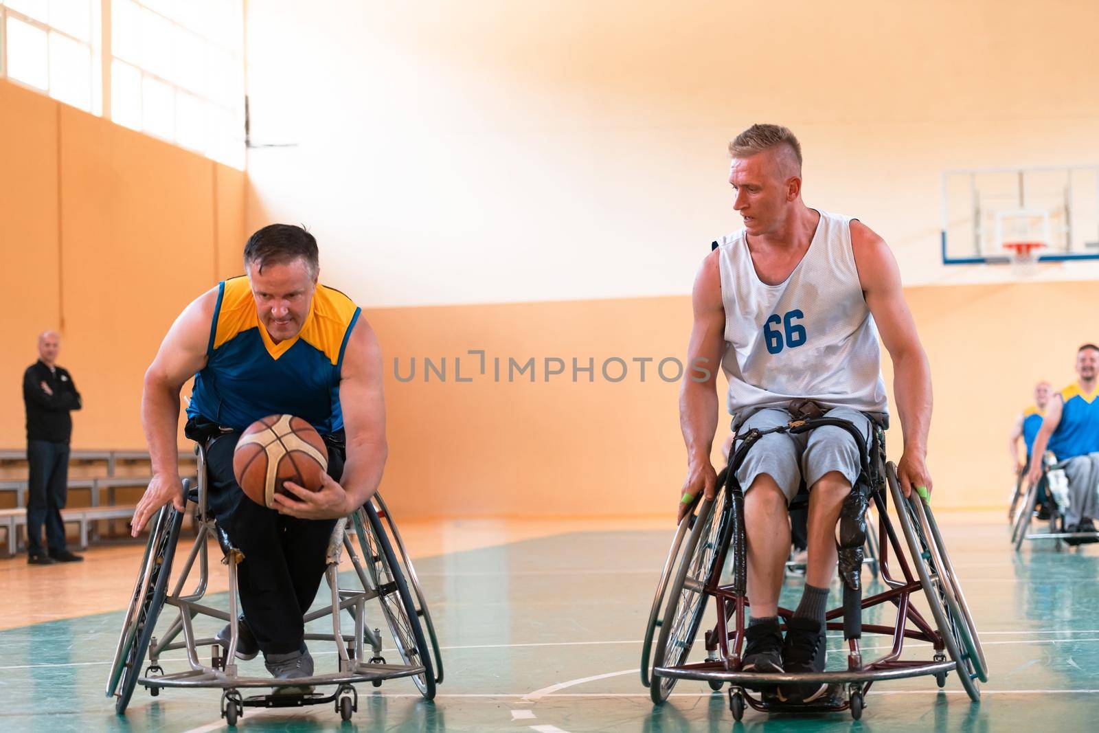 Disabled War or work veterans mixed race and age basketball teams in wheelchairs playing a training match in a sports gym hall. Handicapped people rehabilitation and inclusion concept by dotshock