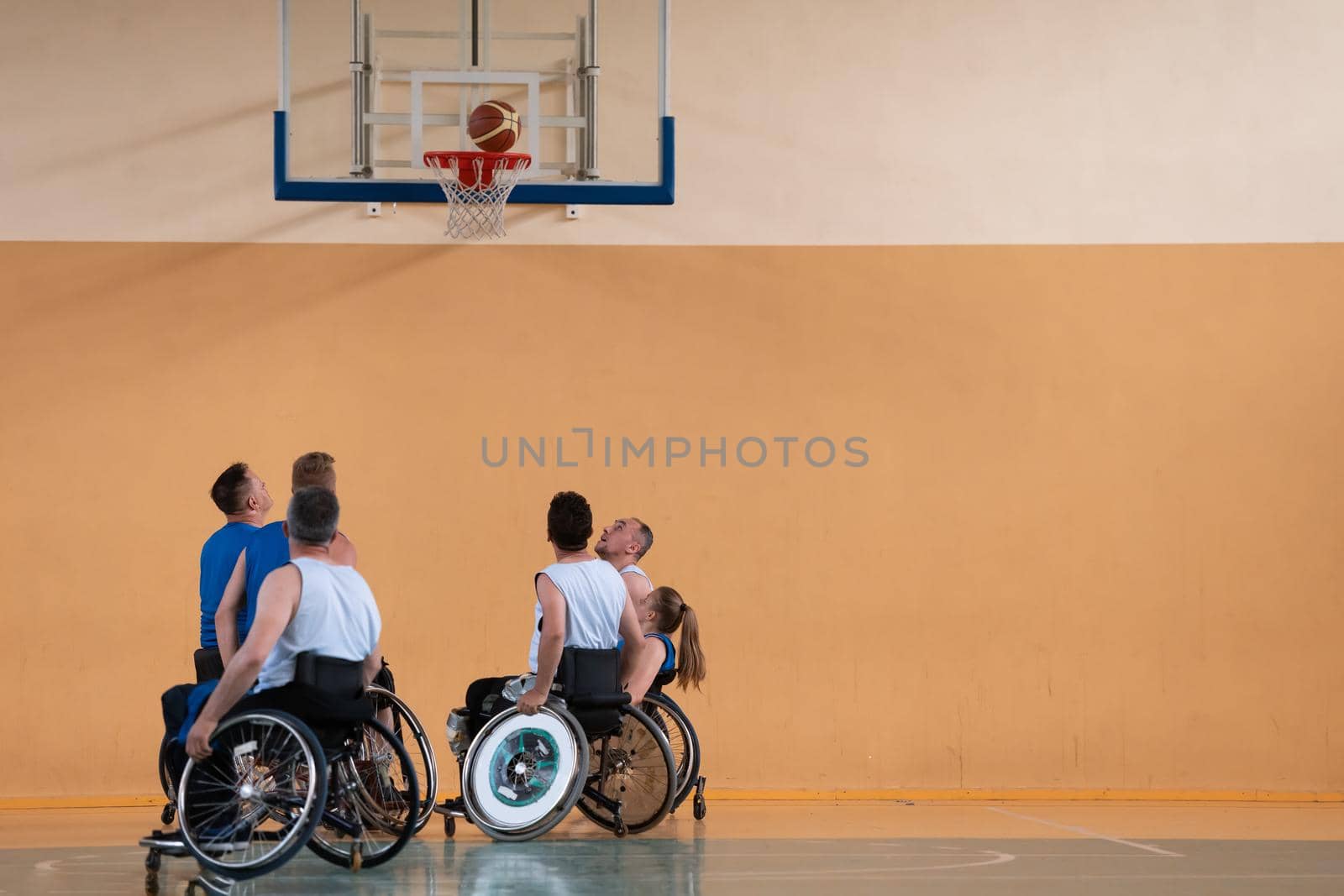 Disabled War veterans mixed race opposing basketball teams in wheelchairs photographed in action while playing an important match in a modern hall.  by dotshock