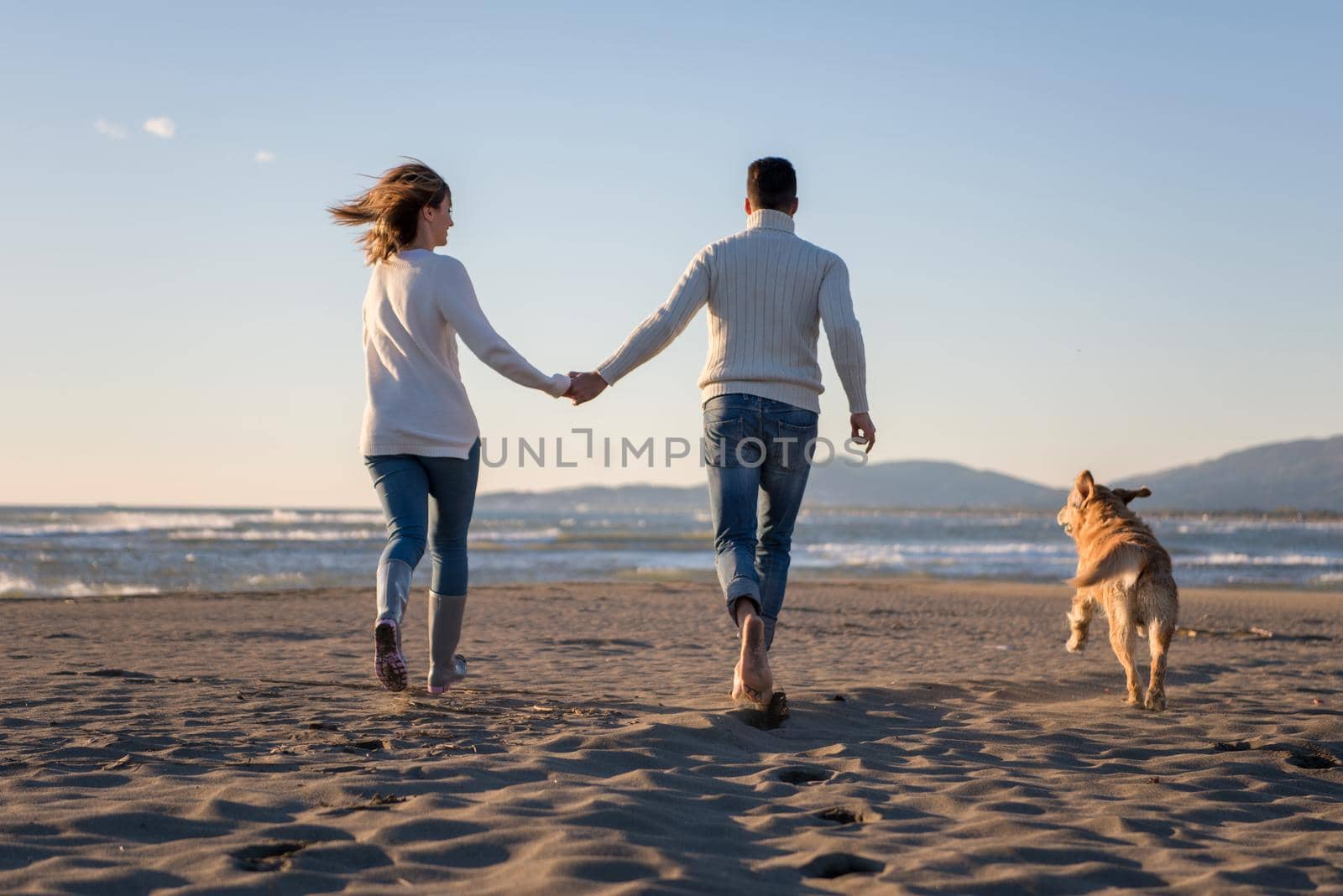 couple with dog having fun on beach on autmun day by dotshock