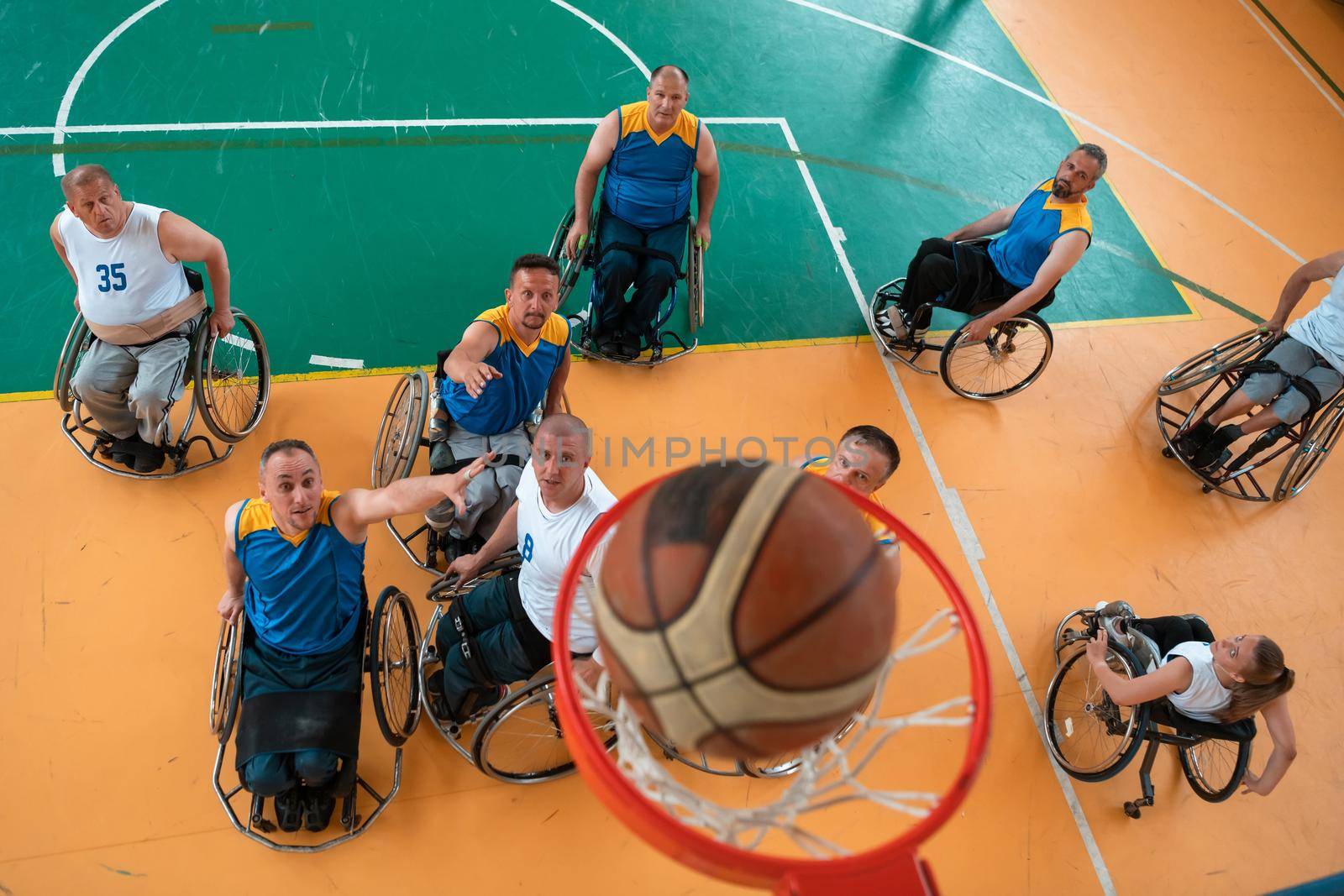 Disabled War or work veterans mixed race and age basketball teams in wheelchairs playing a training match in a sports gym hall. Handicapped people rehabilitation and inclusion concept.  by dotshock