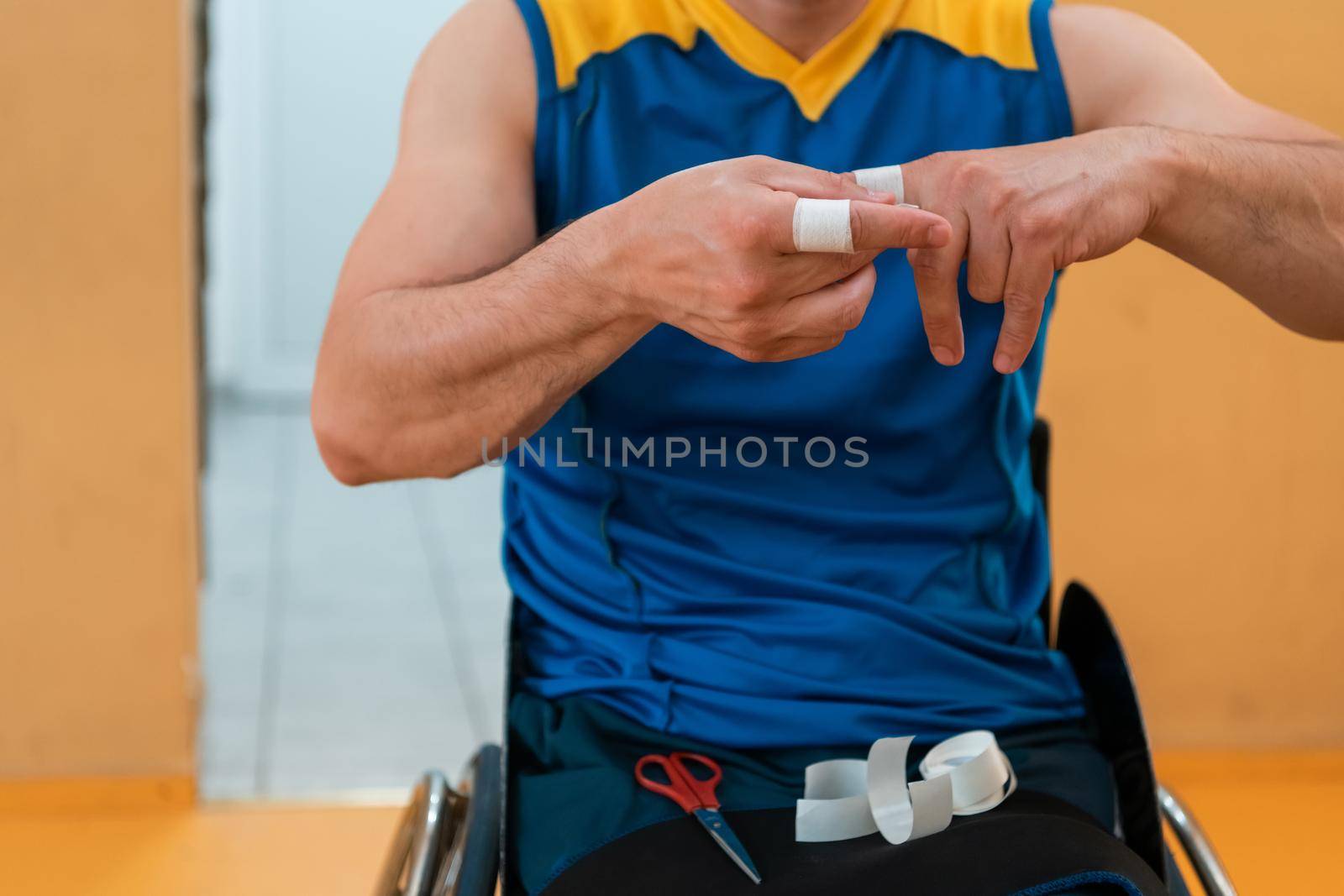 a disabled basketball player puts on a corset and bandages on his arms and fingers in preparation for a game in the arena by dotshock