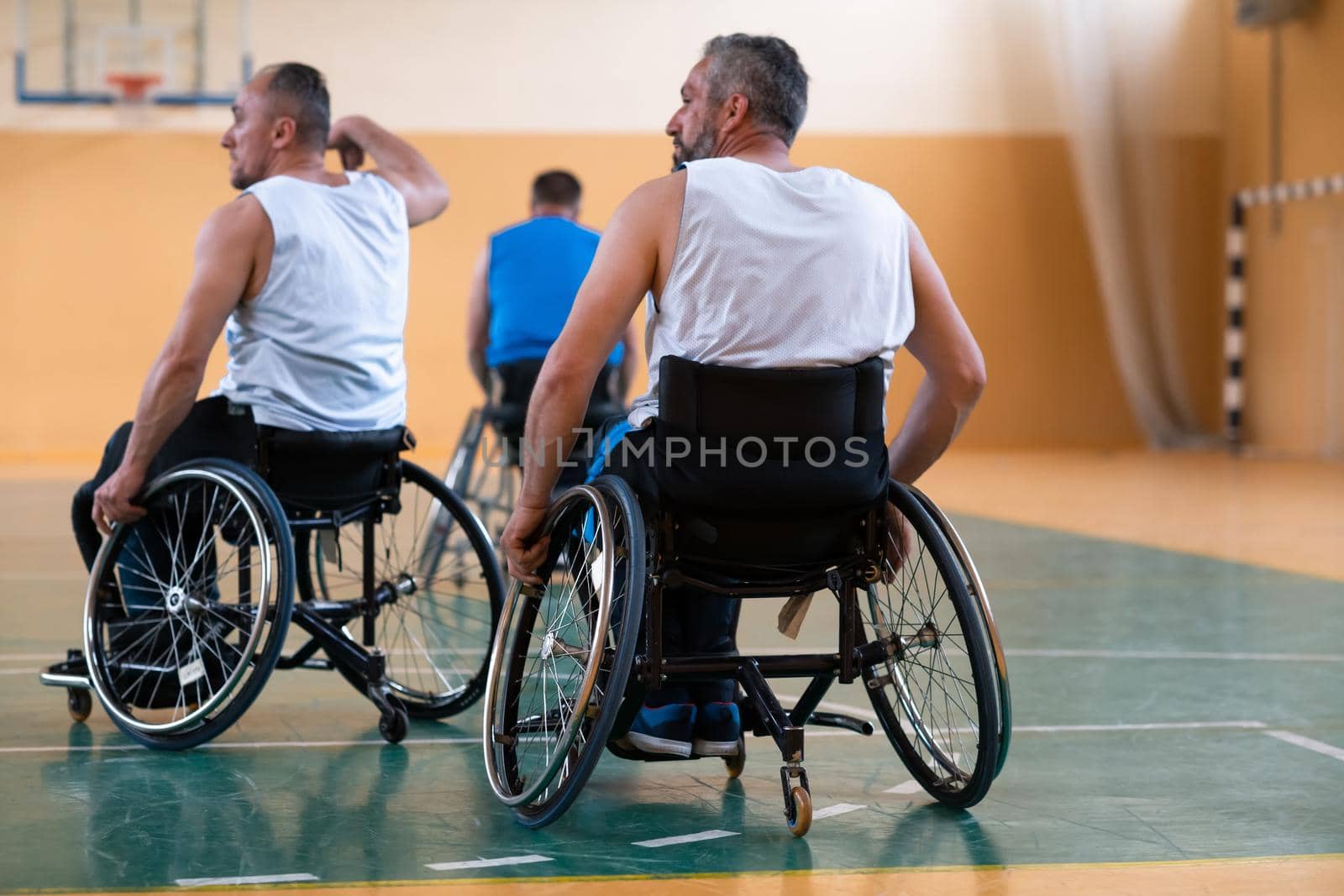 handicapped war veterans in wheelchairs with professional equipment play basketball match in the hall.the concept of sports with disabilities by dotshock