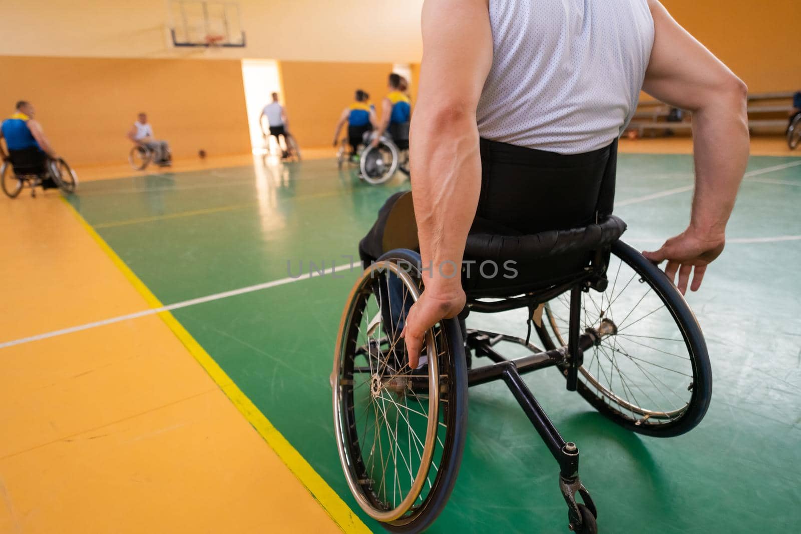 Close up photo of wheelchairs and handicapped war veterans playing basketball on the court by dotshock