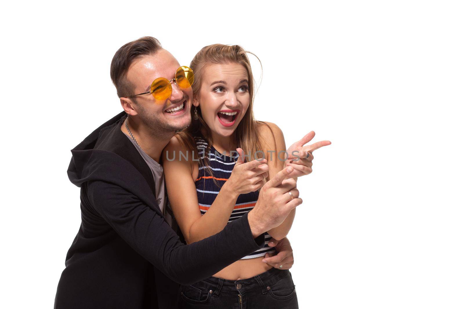 Portrait of the happy couple looking and pointing into the distance, isolated on white background. Emotional young couple laughing at something