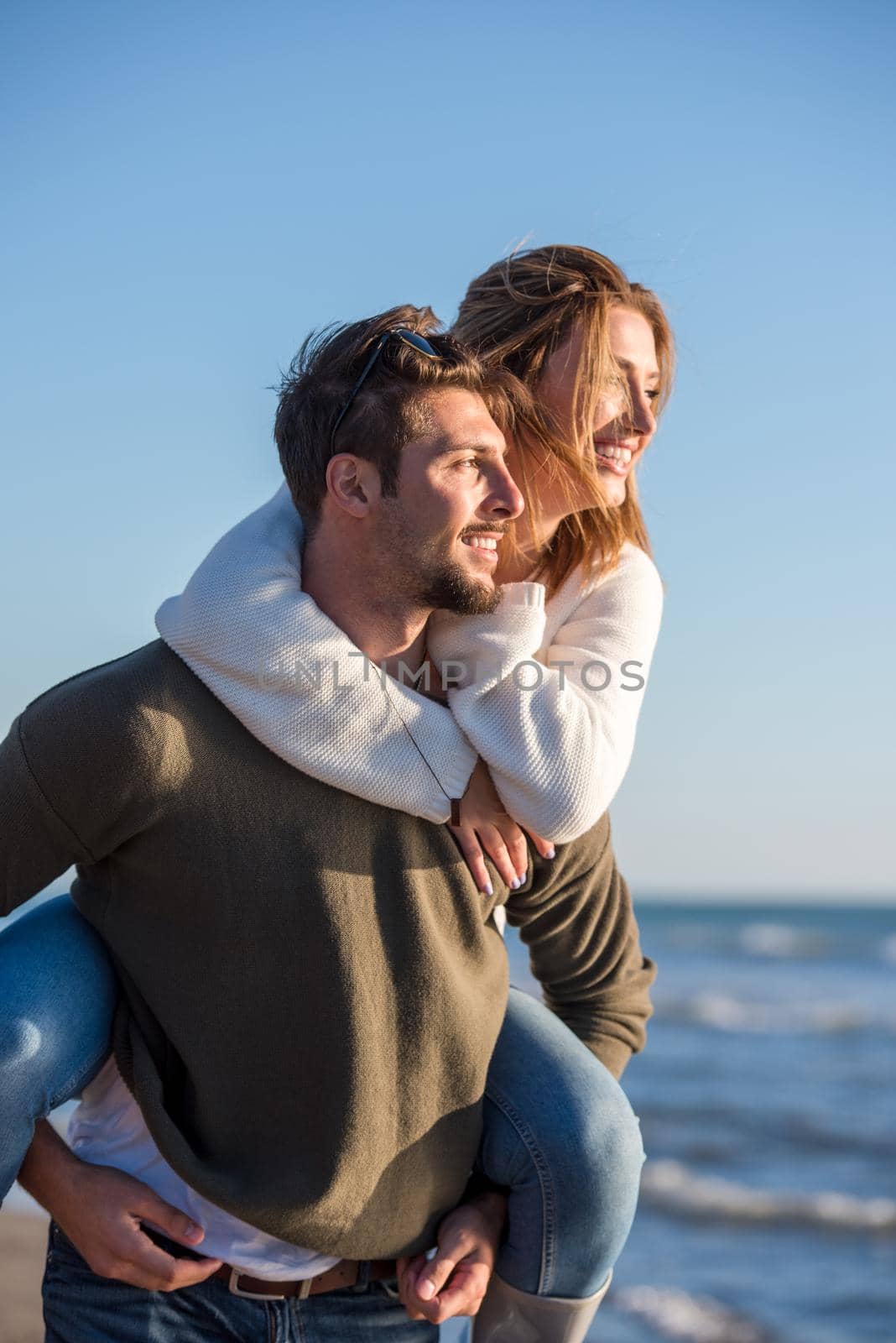 Men Giving Piggy Back Rides to his girlfriend At Sunset By The Sea, autumn time