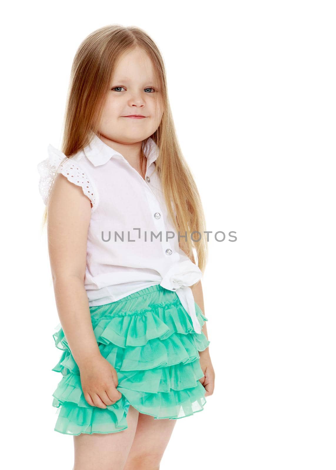 Caucasian little girl with long blond hair below the shoulders ,in a short green skirt . The little girl turned sideways to the camera . close-up - Isolated on white background