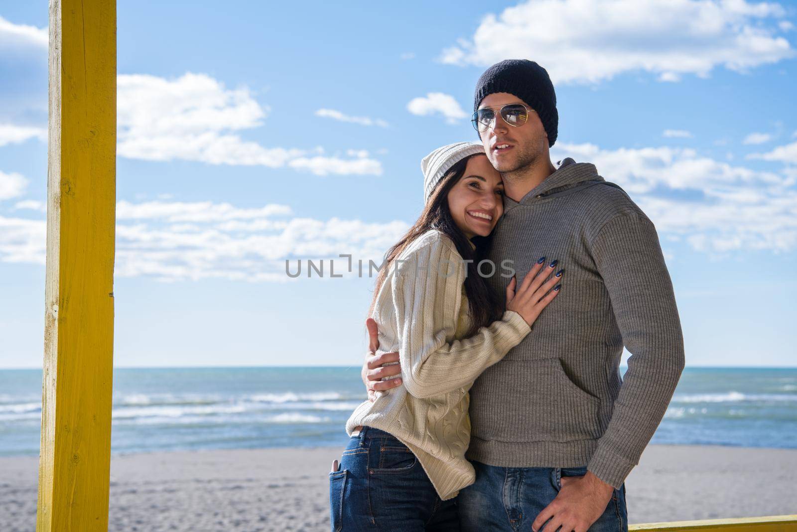 Happy couple enyojing time together on beach during autumn day