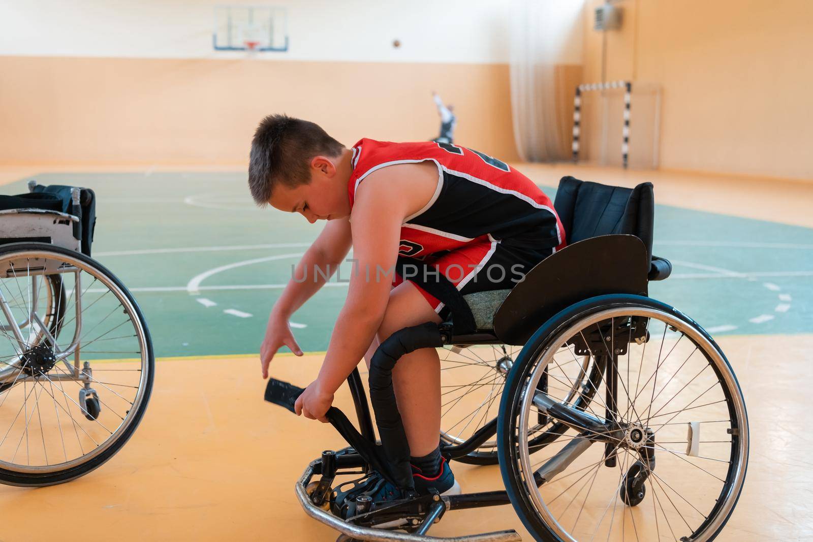 the boy sits in a wheelchair and prepares for the basketball start of the game in the big arena. Selective focus 