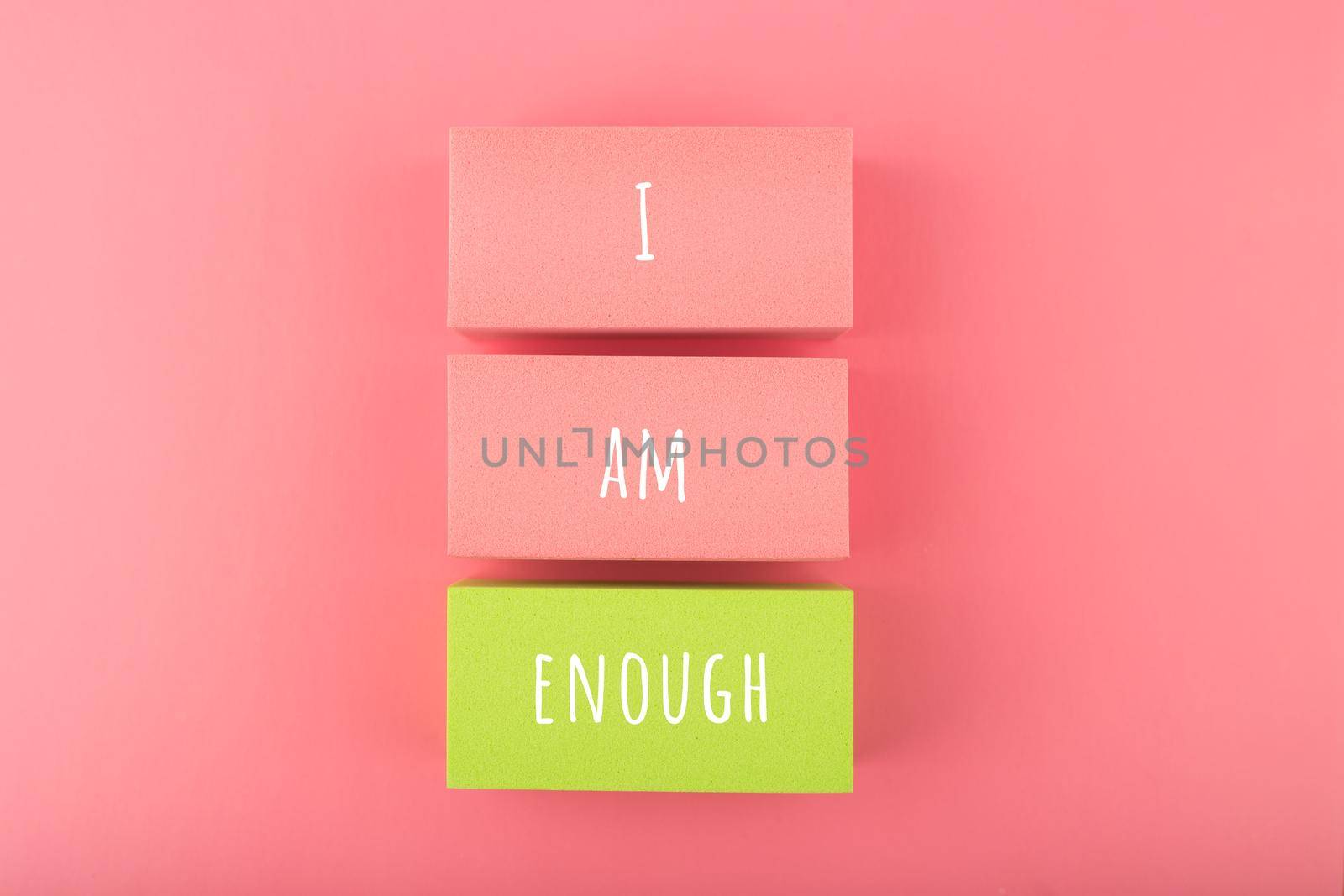 I am enough concept with words written on colorful rectangles against bright pink background. Mental health and self love concept