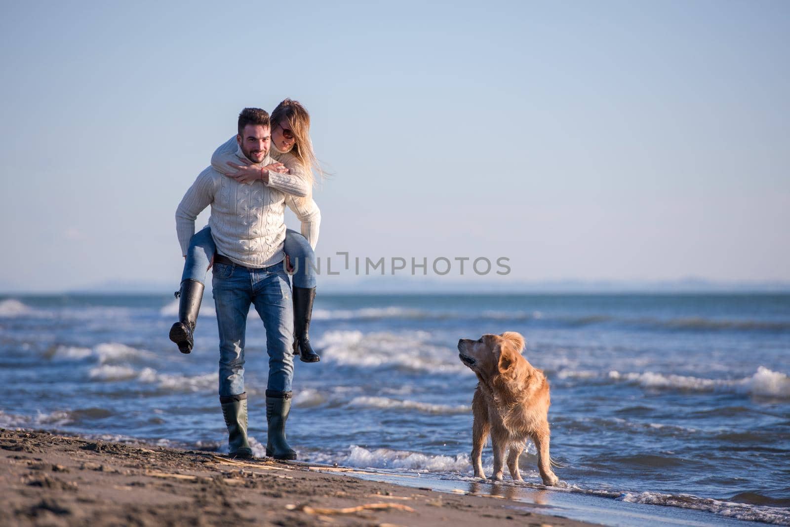 couple with dog having fun on beach on autmun day by dotshock