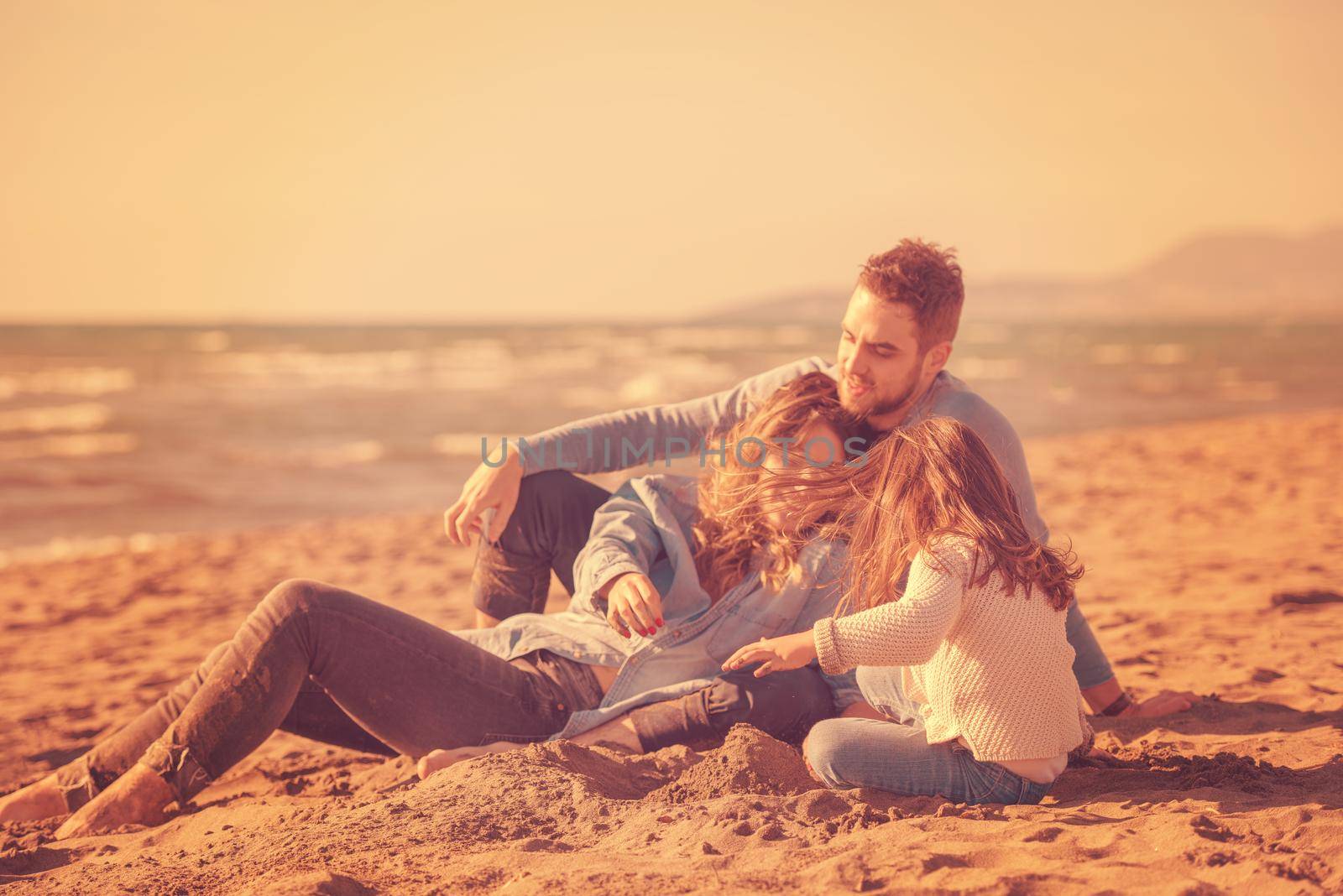 Family with kids resting and having fun at beach during autumn day filter