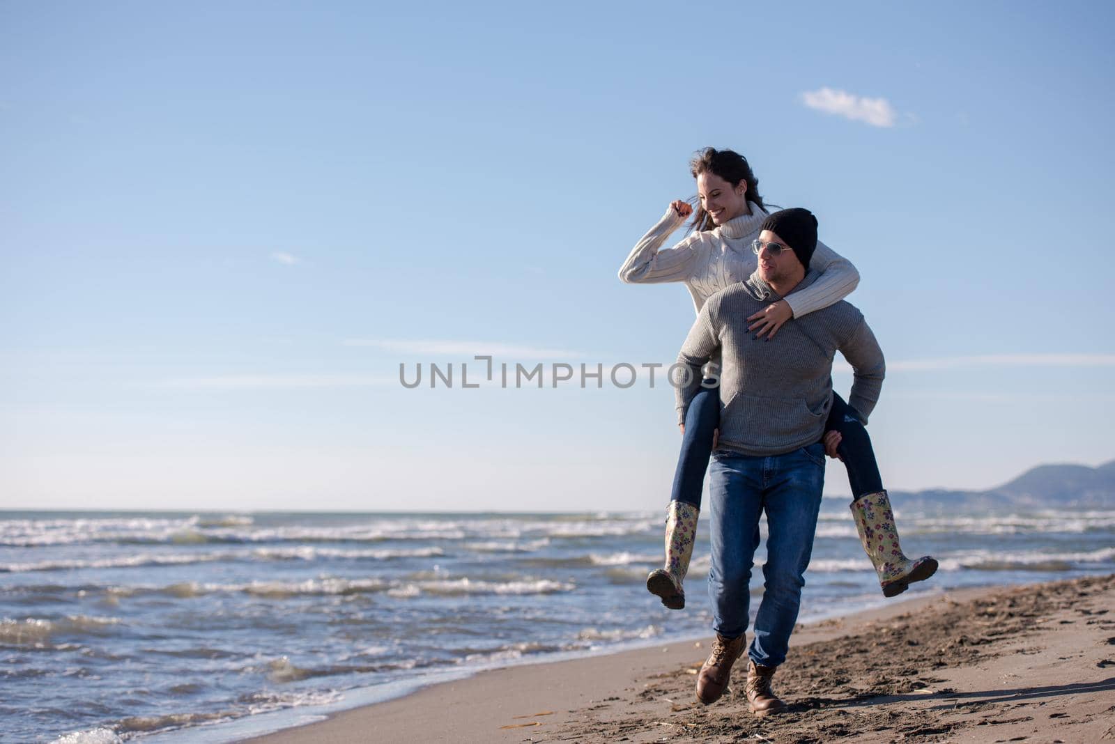 Men Giving Piggy Back Rides his girlfriend At Sunset By The Sea, autumn time