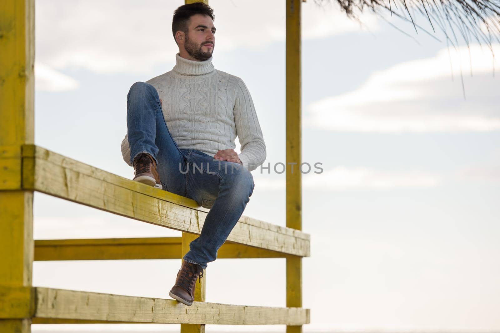 Young man on the beach. The guy enjoying the warm autumn day. Portrait of man near the water