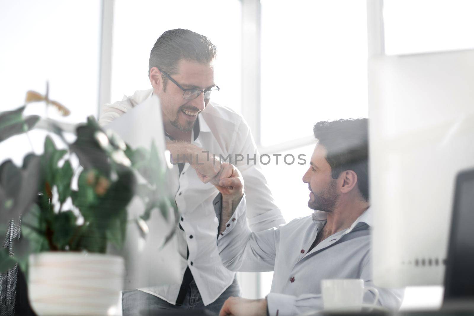 business background.Two smiling male colleagues giving fist bumps. concept of achieving a business goal