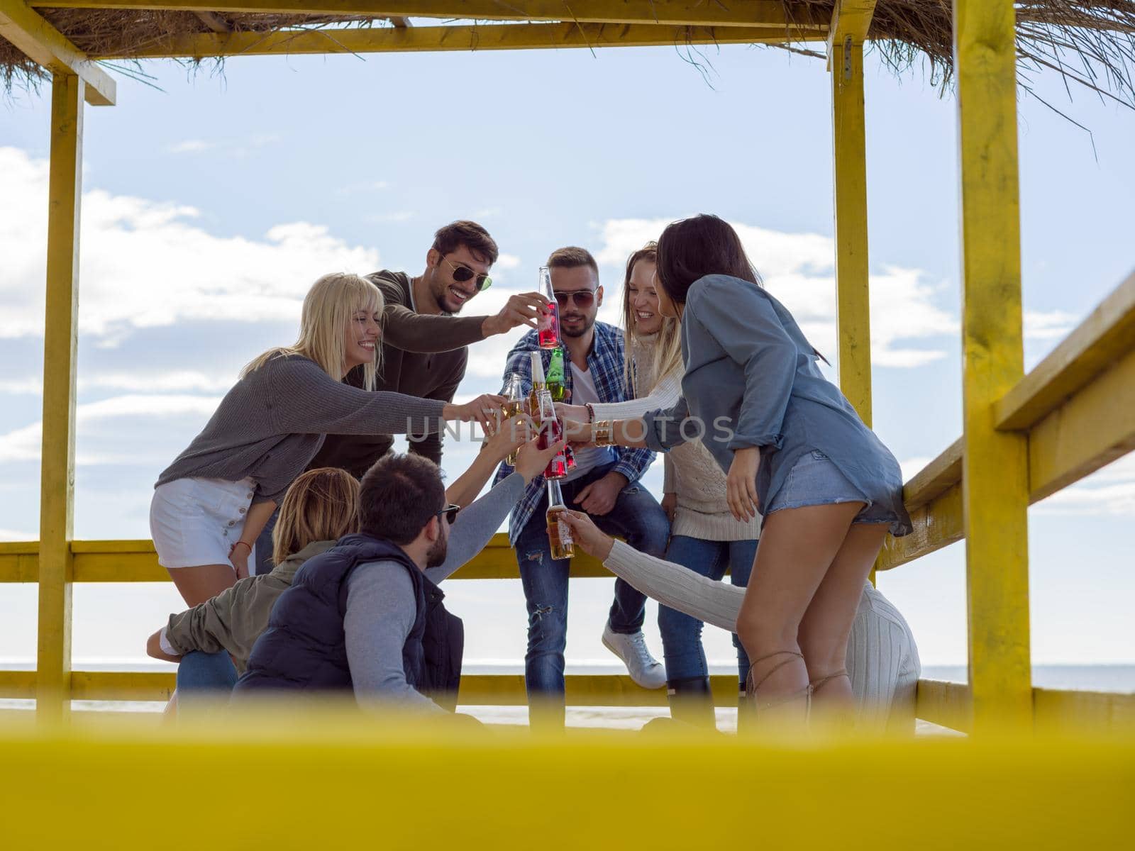 Group of friends having fun on autumn day at beach by dotshock