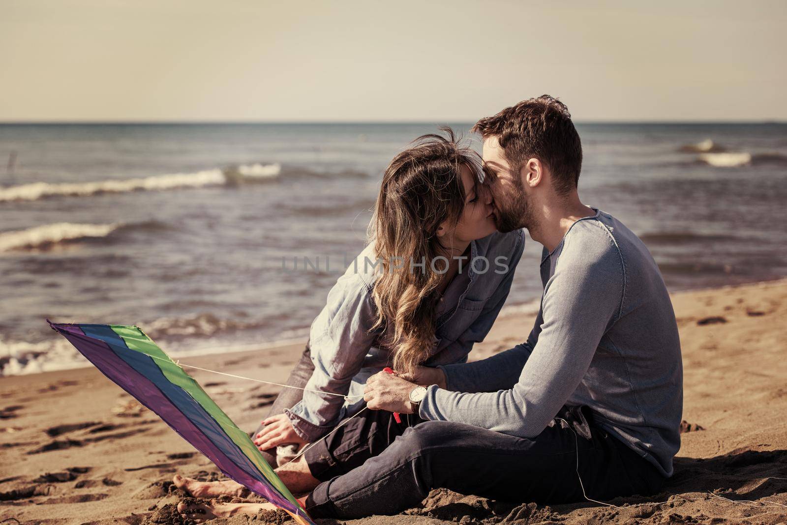 Young Couple having fun and Playing With A Kite On The Beach at autumn day filter