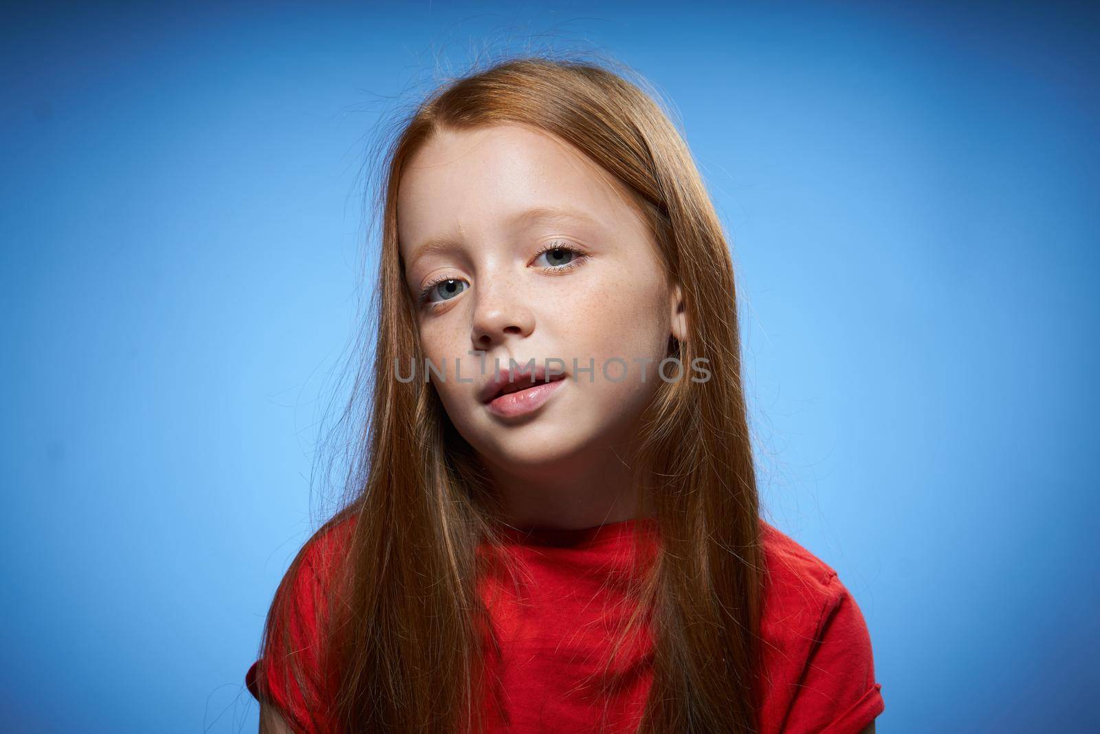 cheerful cute red-haired girl childhood blue background. High quality photo
