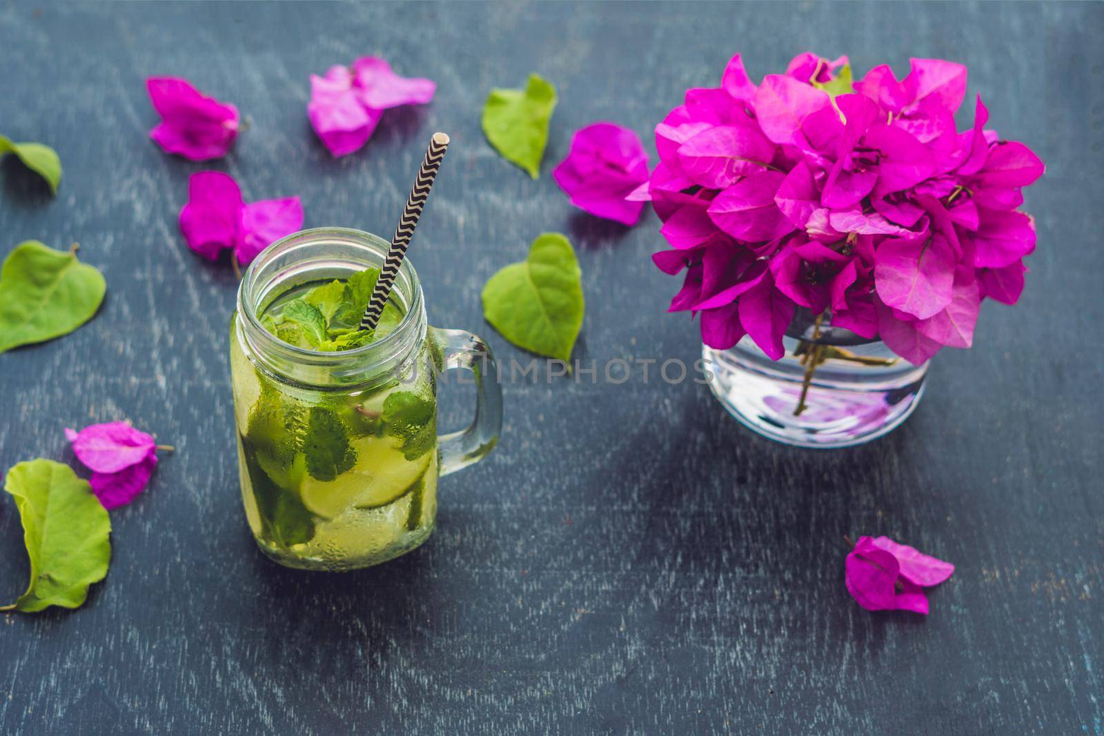 Spring purple flowers and spring mojito drink on an old wooden background.