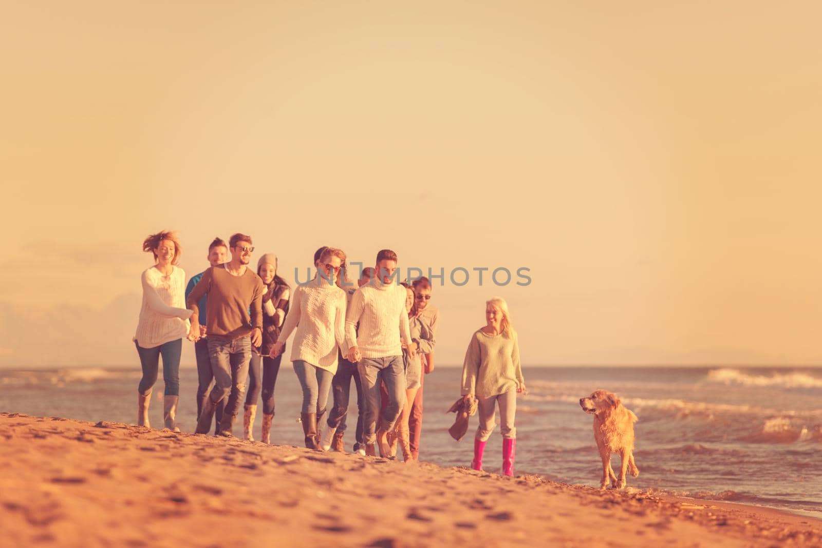 group of young friends spending day together running on the beach during autumn day