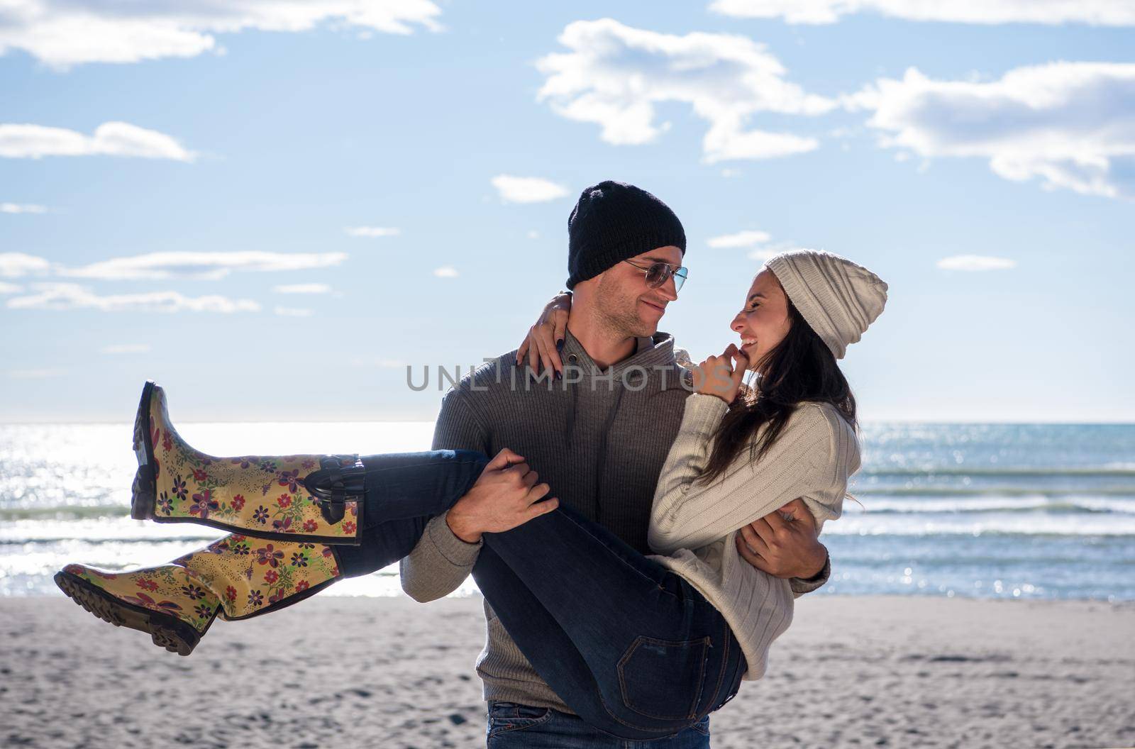 Happy couple enyojing time together on beach during autumn day