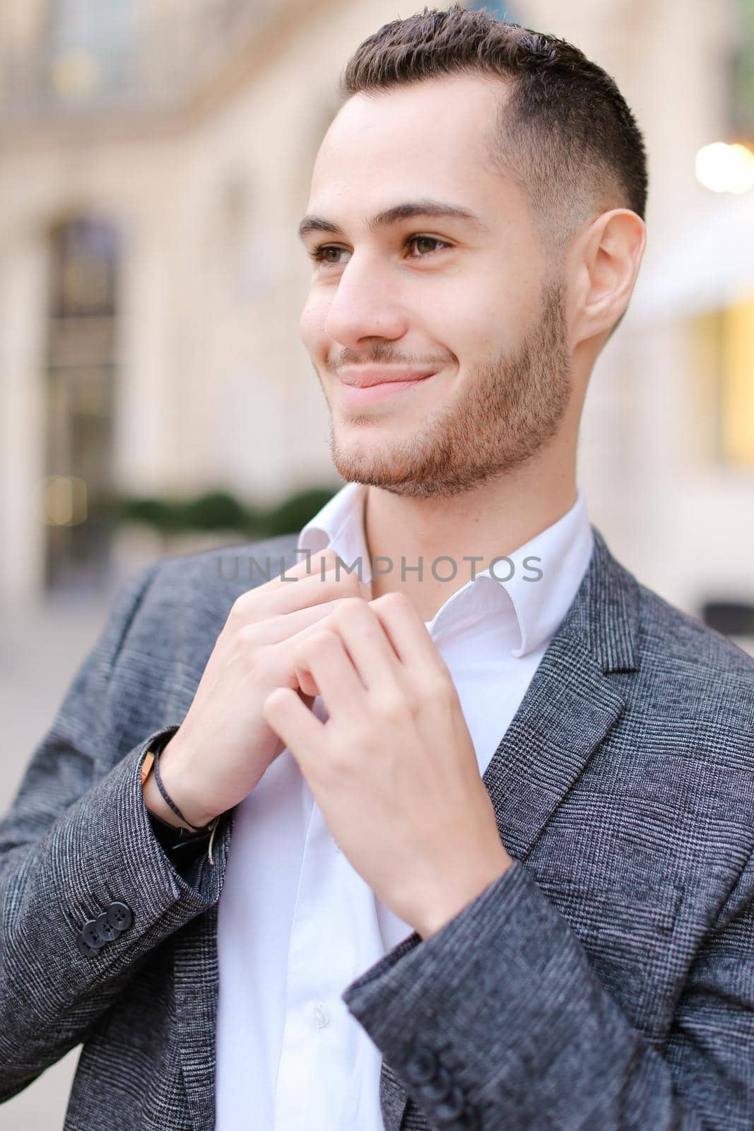 Portrait of young cacuasian male person wearing suit standing outdoors. Concept of fashion and businessman, urban life.