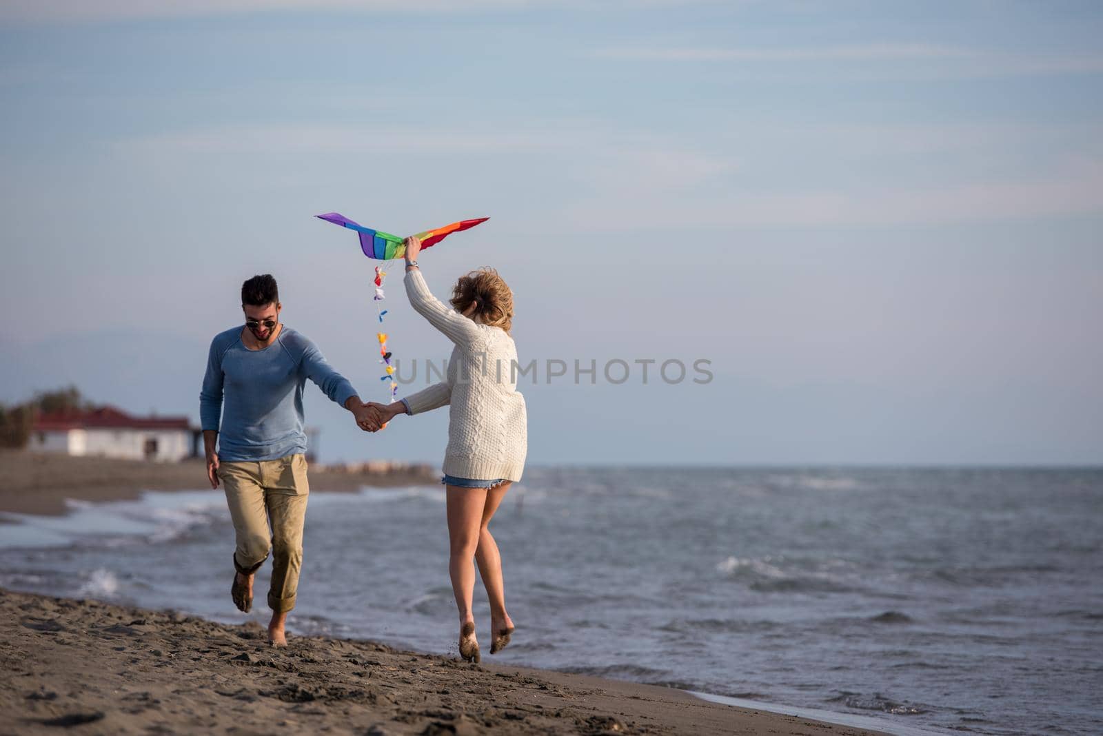 Young Couple having fun and Playing With A Kite On The Beach at autumn day