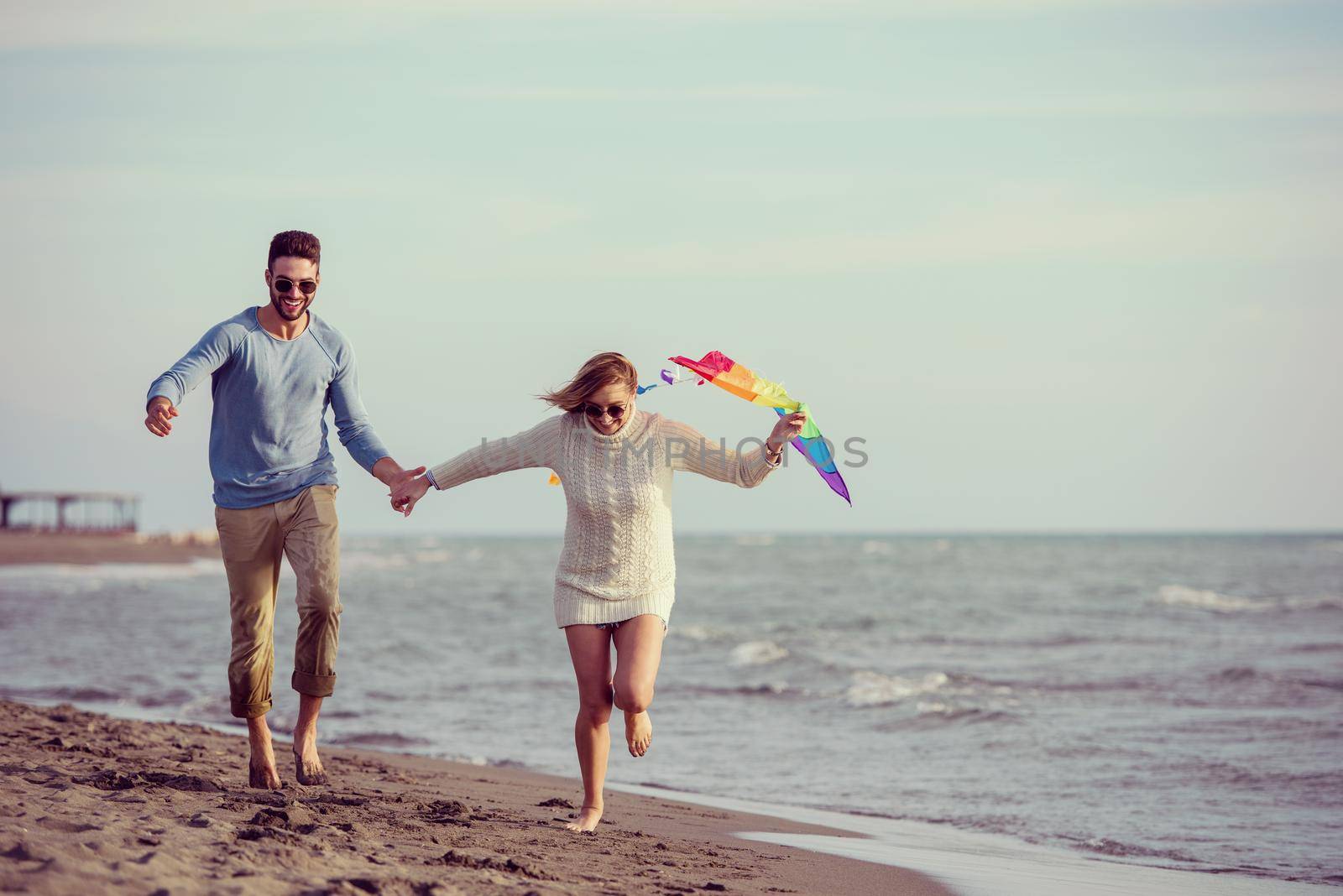 Young Couple having fun and Playing With A Kite On The Beach at autumn day filter