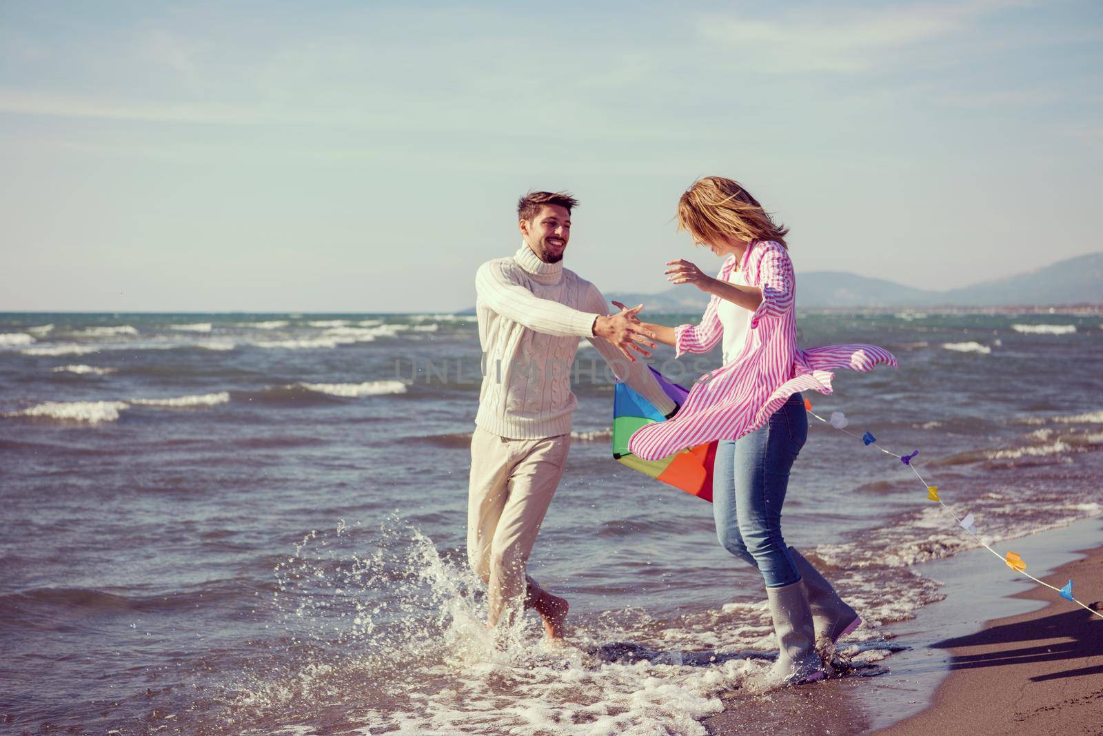 Young Couple having fun and Playing With A Kite On The Beach at autumn day filter