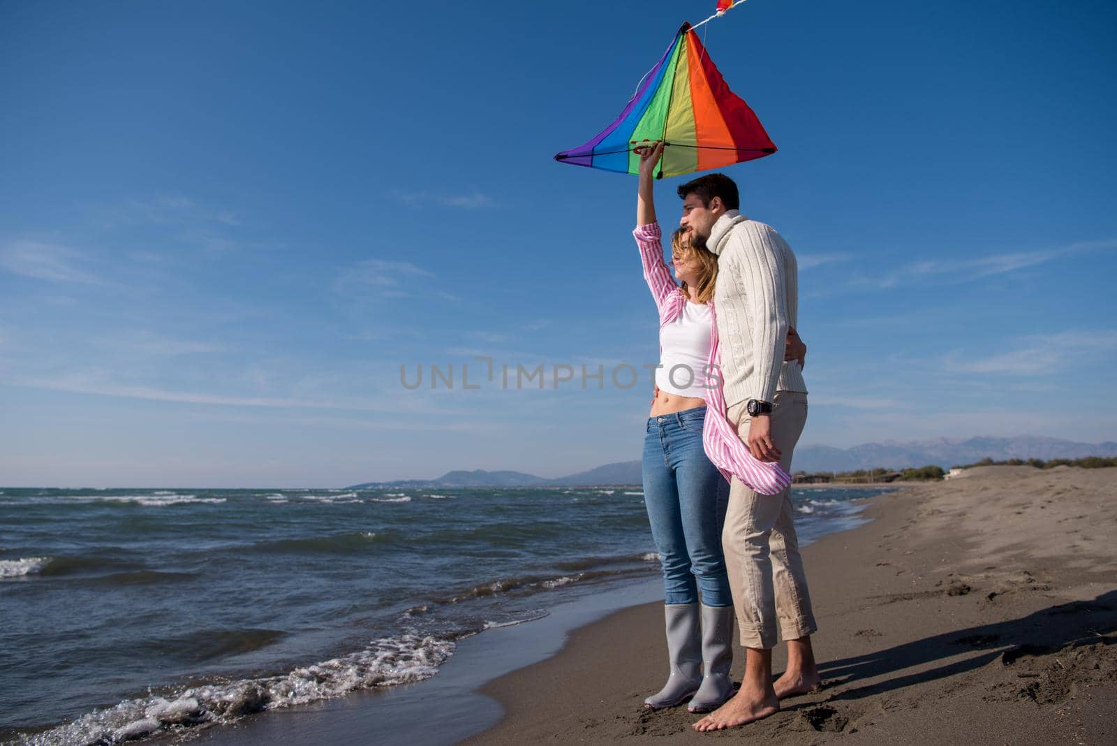 Young Couple having fun and Playing With A Kite On The Beach at autumn day