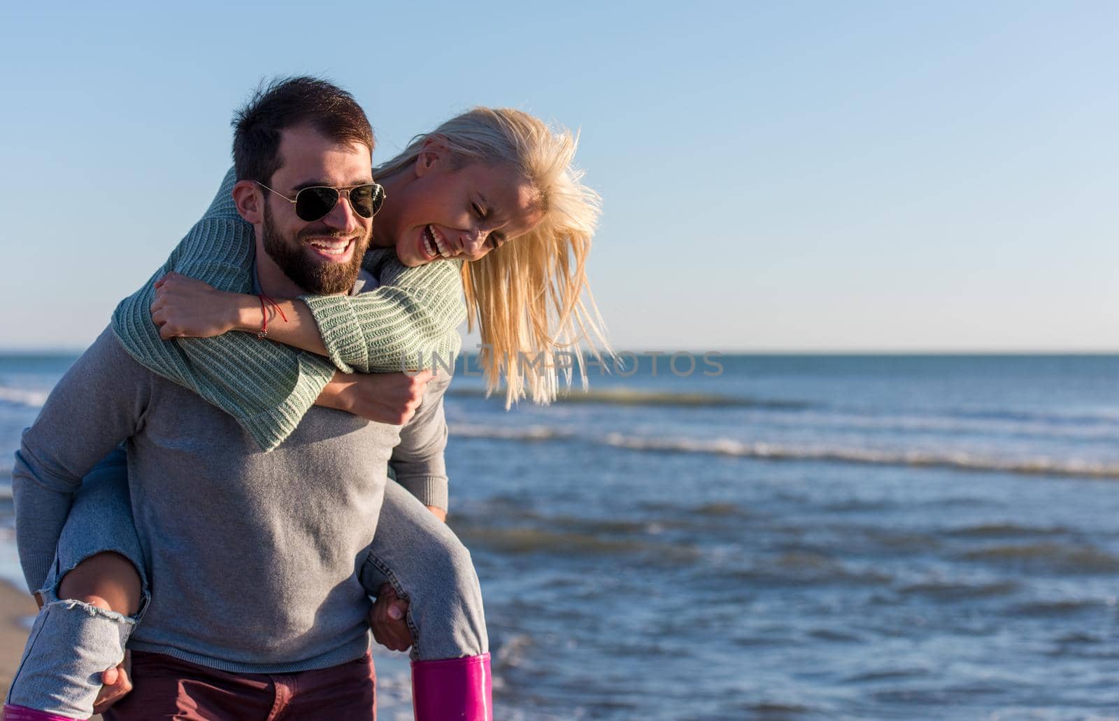 Men Giving Piggy Back Rides to his girlfriend At Sunset By The Sea, autumn time