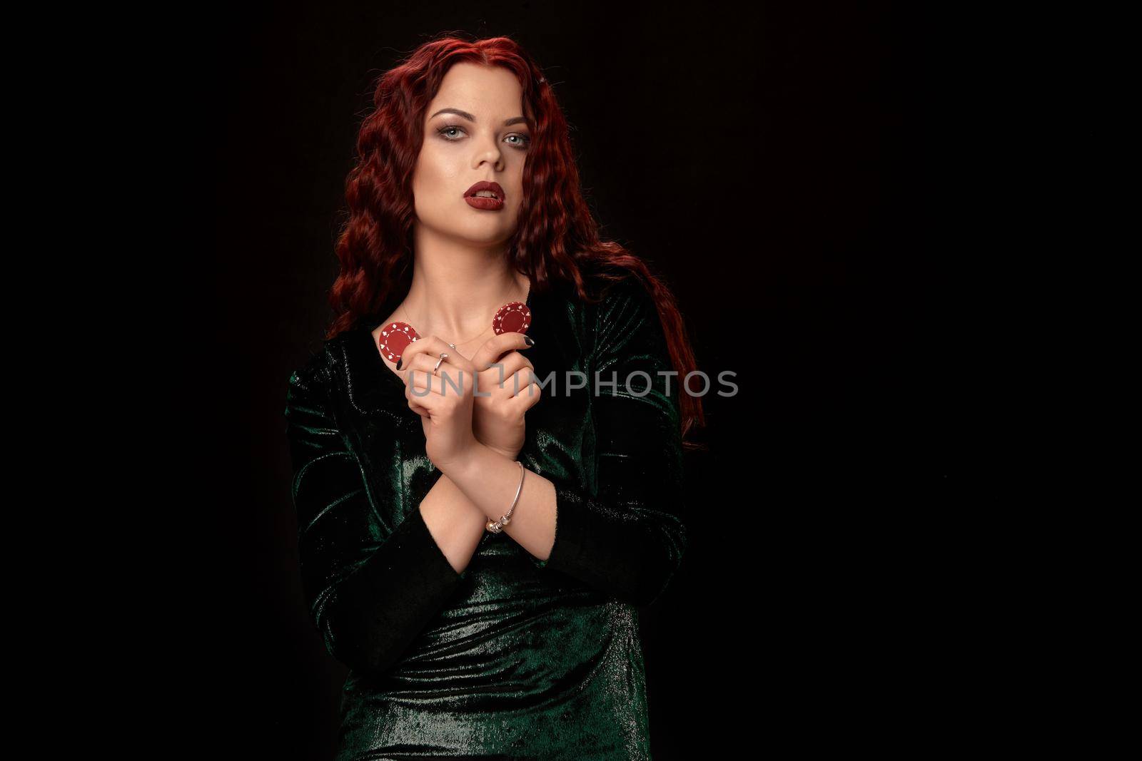 Young redheaded woman whith a red lips, curly hair and chips in her hand, over black. Win casino holdem poker slots