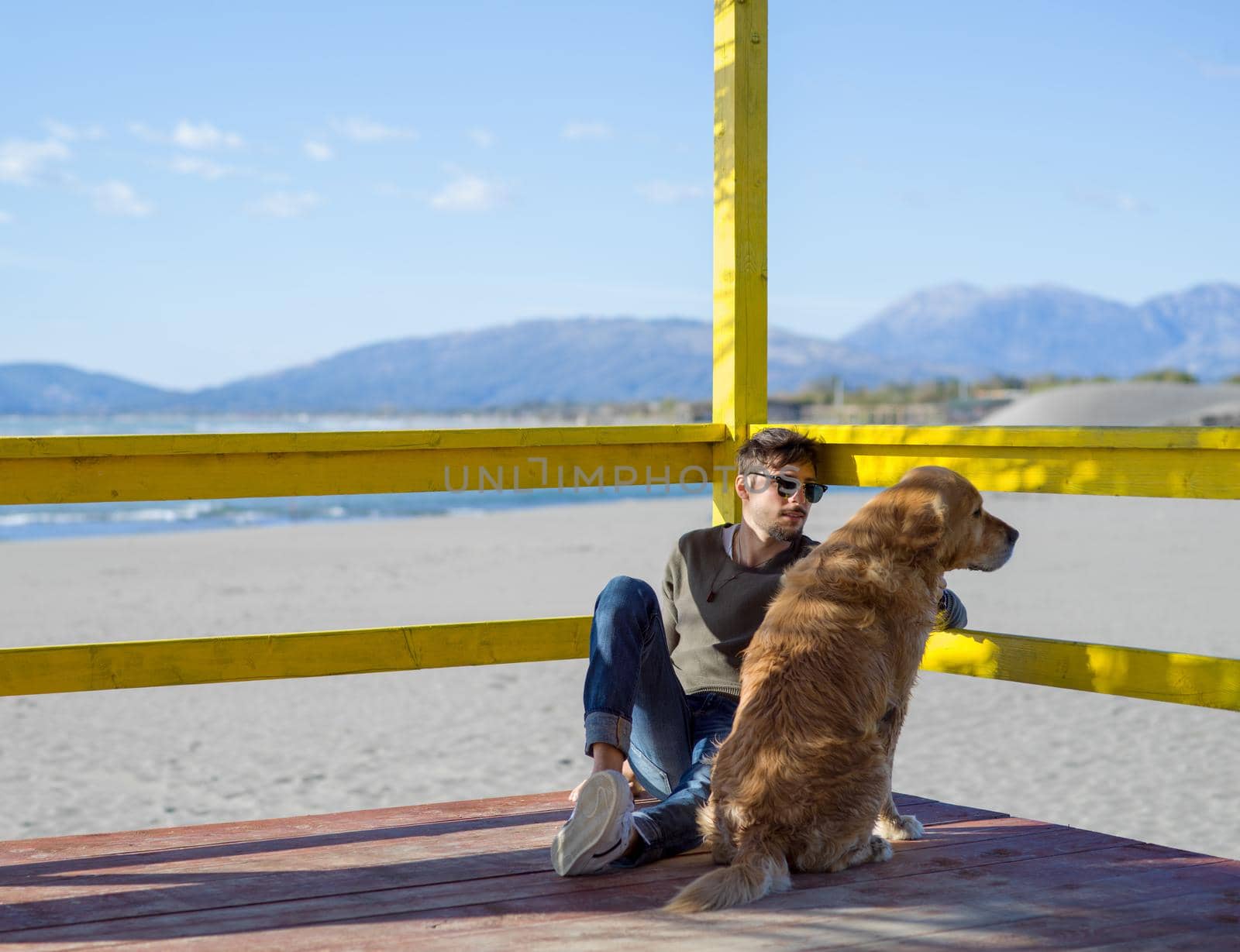 man with dog enjoying free time on the beach at autumn day