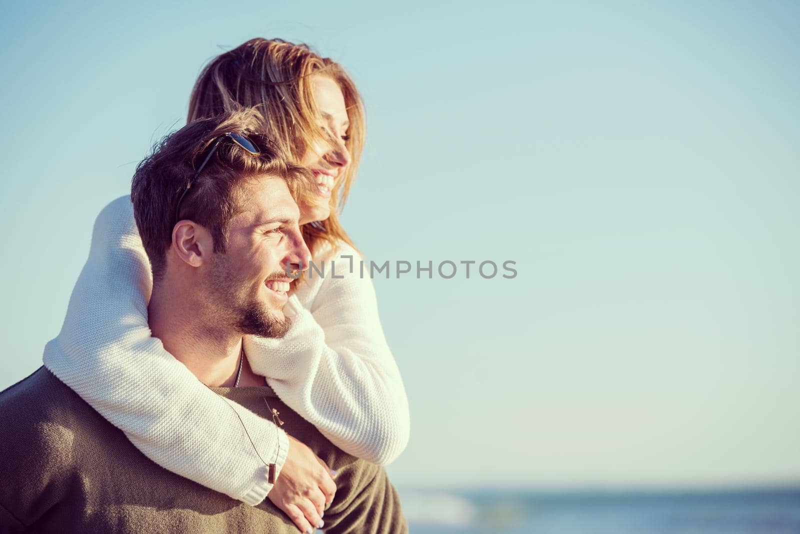 Men Giving Piggy Back Rides to his girlfriend At Sunset By The Sea, autumn time